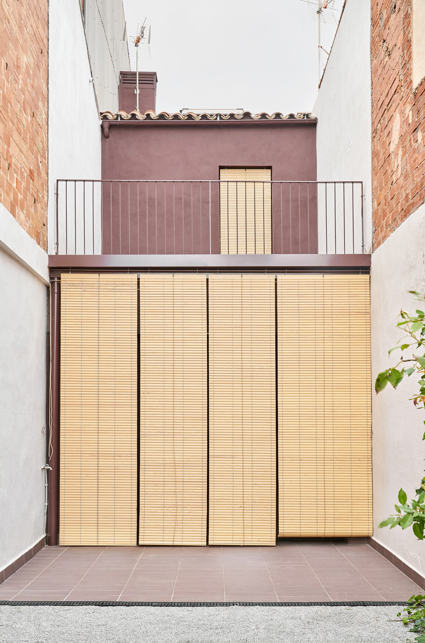 Rear facade with retractable timber slatted shutters fully closed over glazed openings between brick party walls