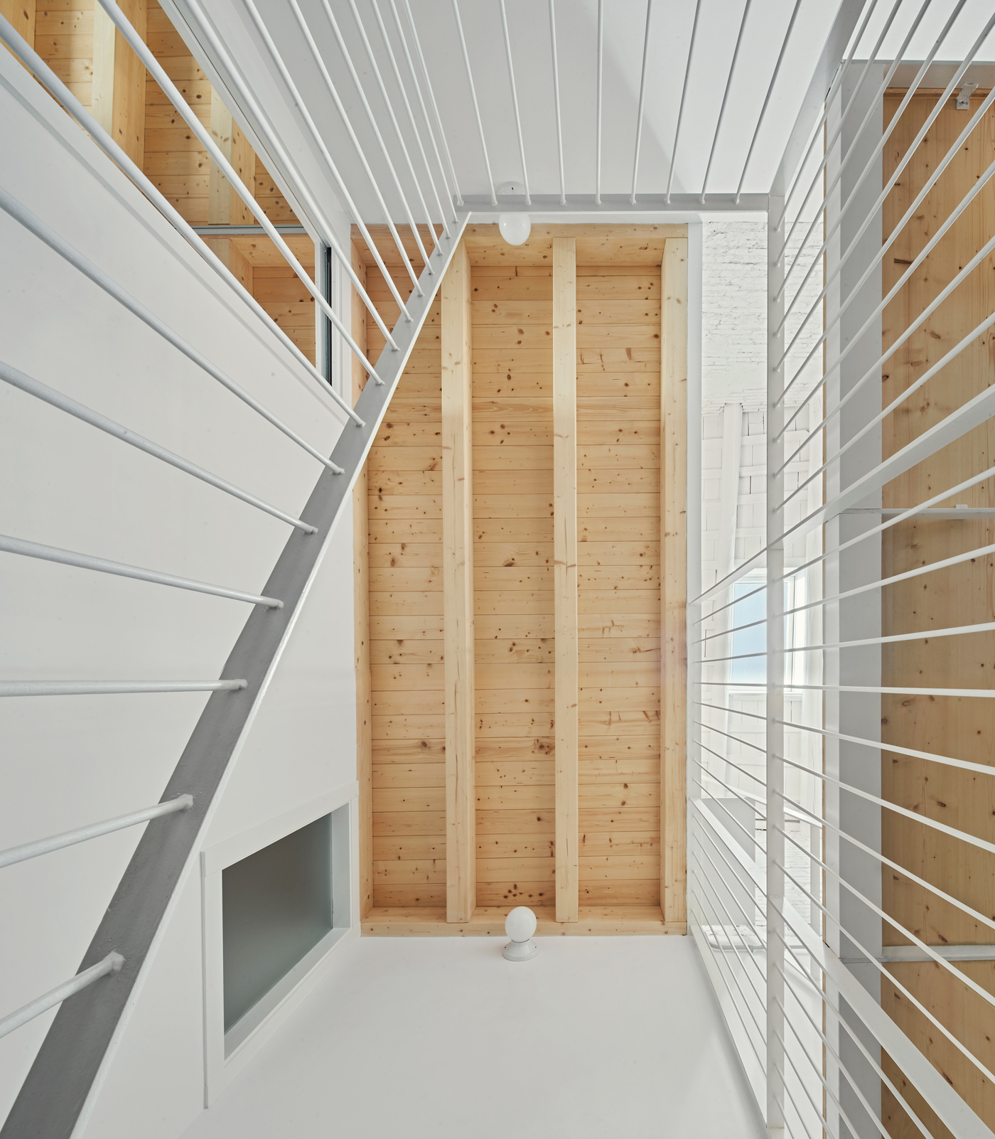 Three-story atrium with white metal railings and vertical timber-clad columns framing the central void
