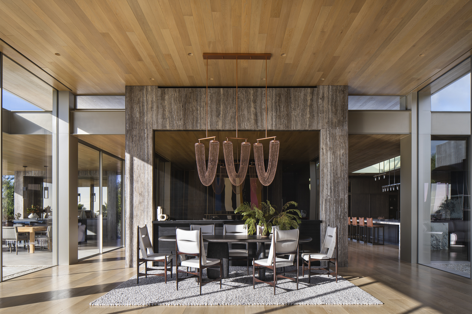 Covered dining area with timber ceiling, weathered wood-clad columns, and chandelier above a round table