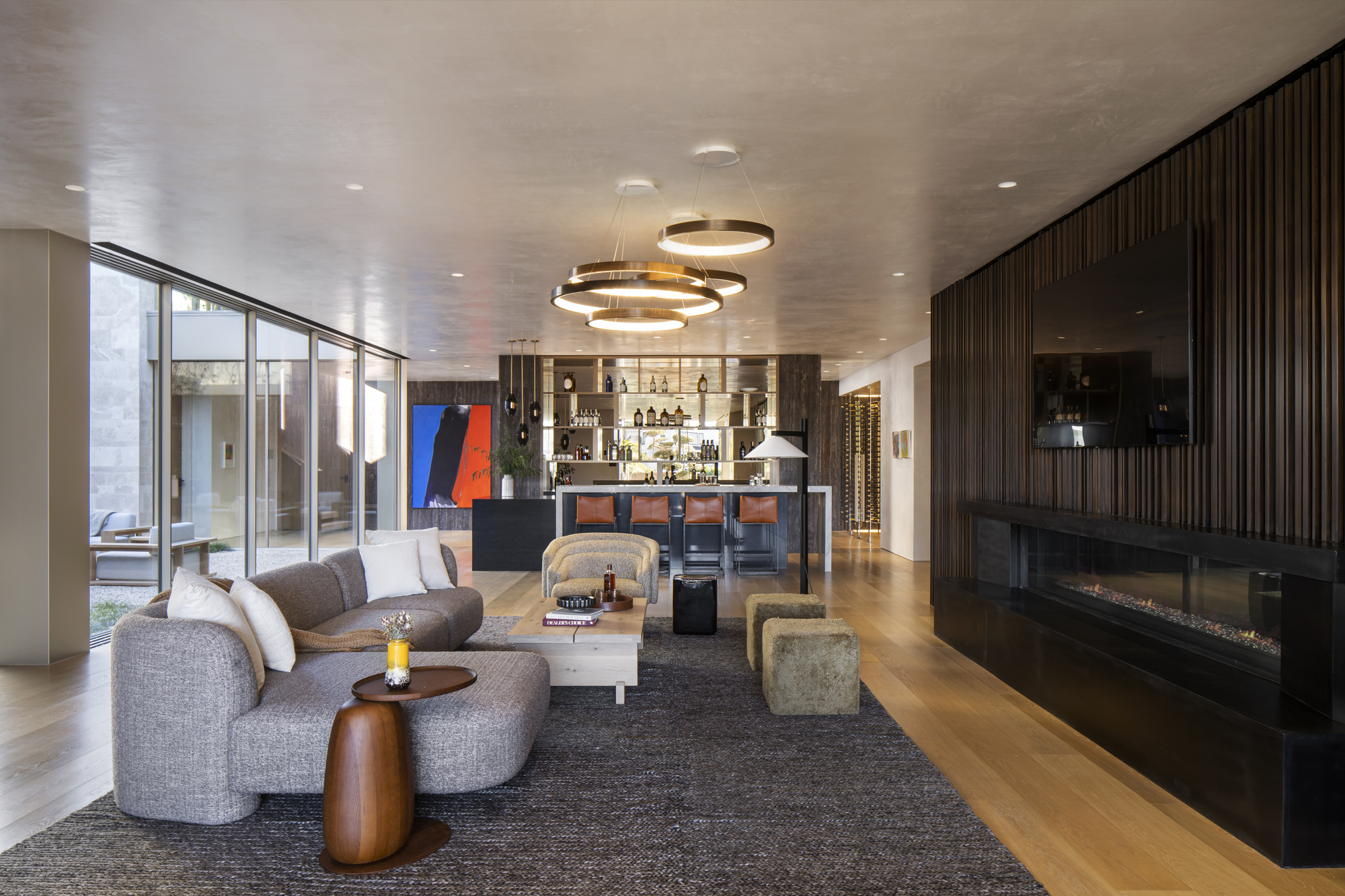 Living room with ring pendant lights, grey upholstered seating, and linear fireplace in dark millwork