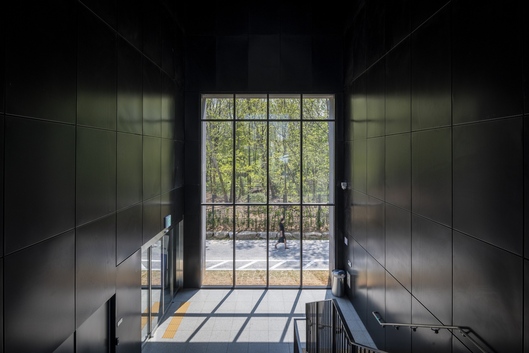 Double-height entrance lobby with gridded steel window framing a view of bare trees beyond