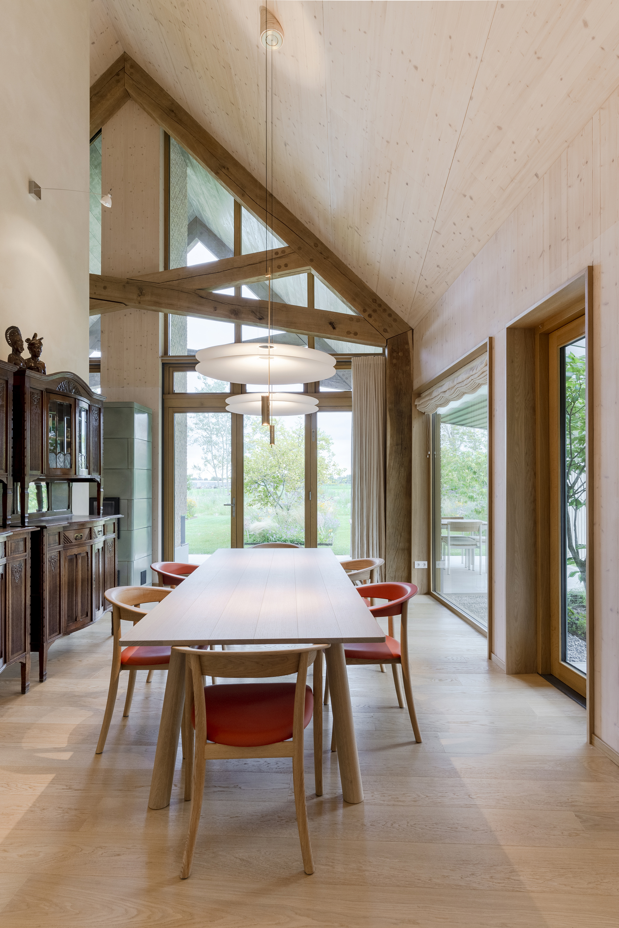 Dining room with exposed timber trusses and pendant light beneath a vaulted plywood ceiling