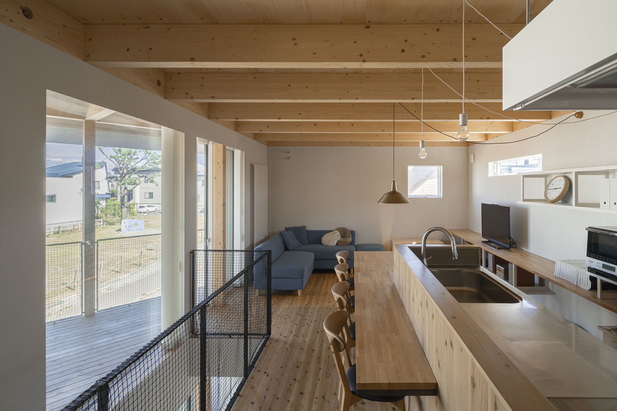 Kitchen island with stainless counter under exposed timber ceiling joists and pendant lights