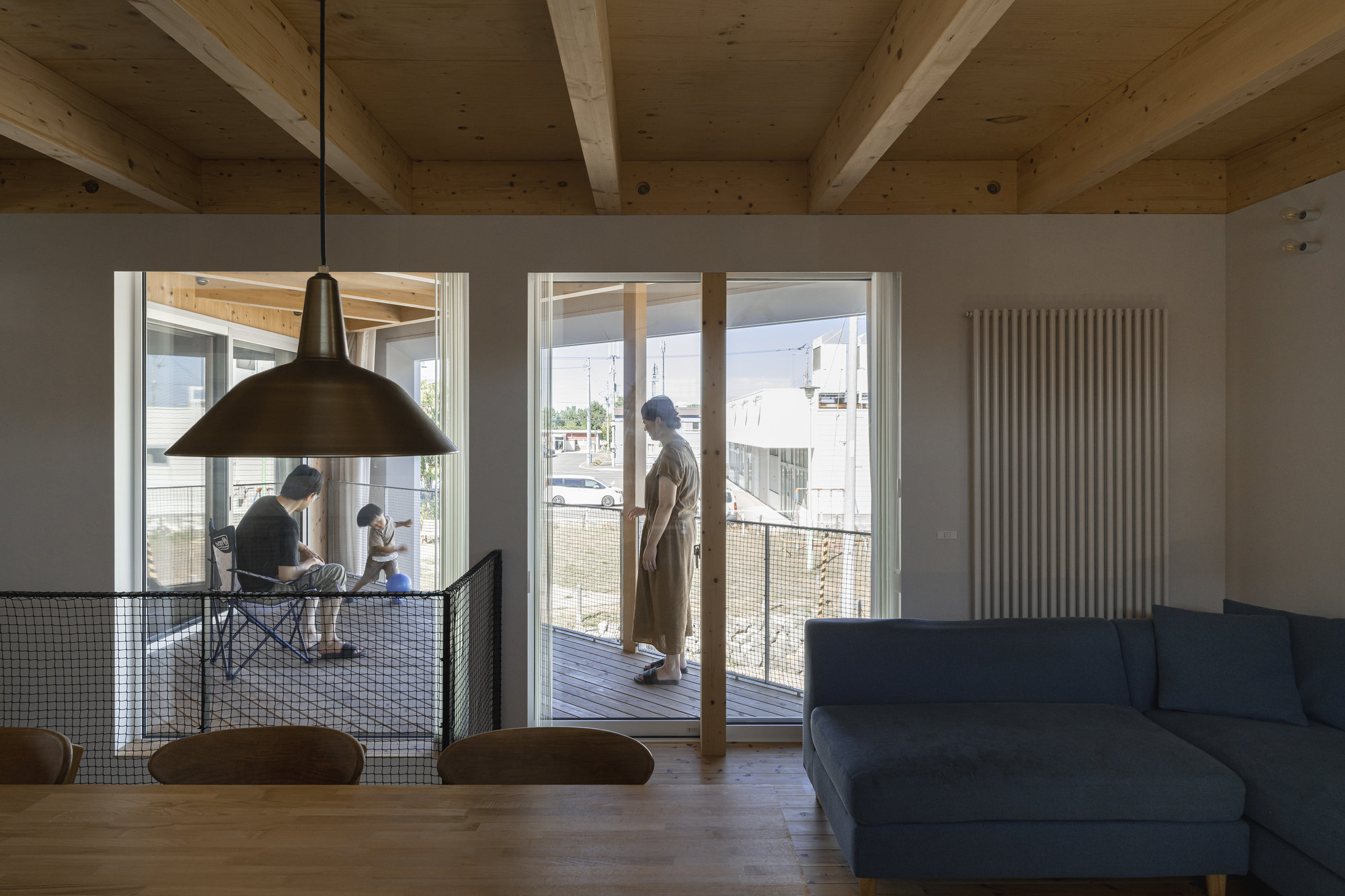 Living space with glass doors opening to the timber deck and family gathered at the dining table