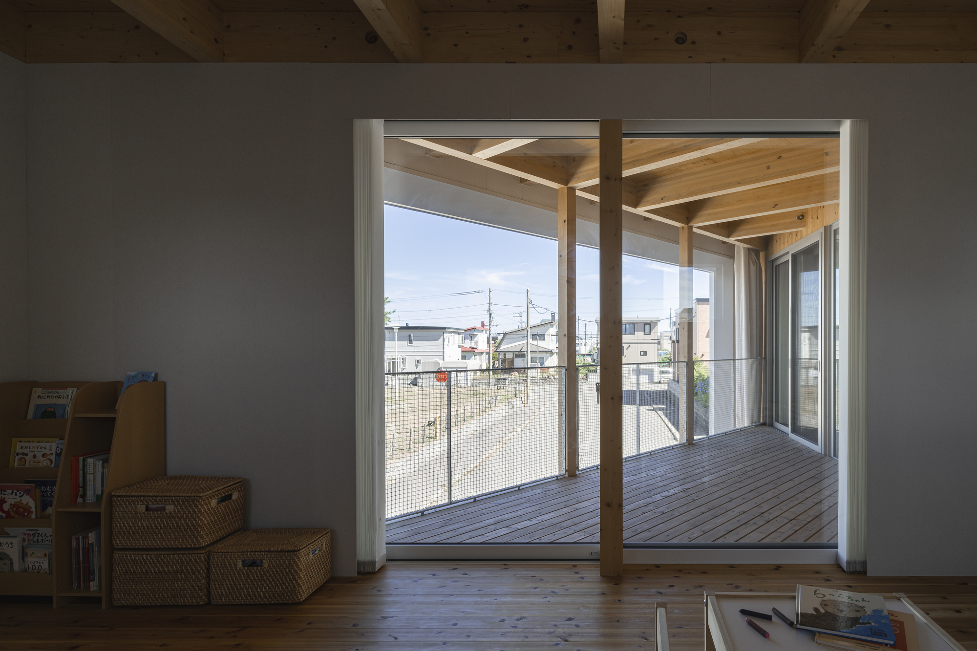 Interior view through sliding doors to the covered timber deck with exposed beam ceiling