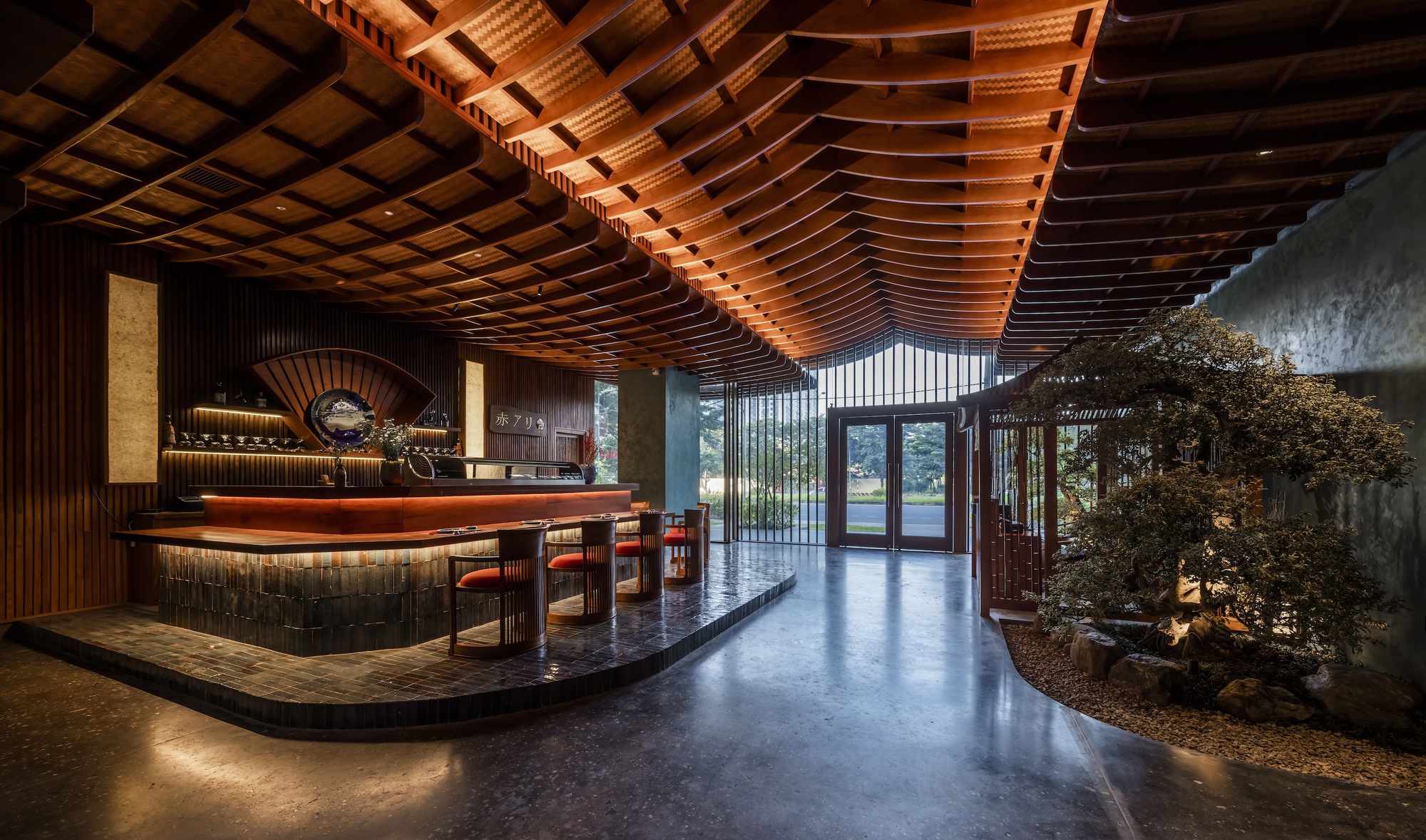Reception area with curved timber counter and undulating wood-slat ceiling above an interior courtyard with tree