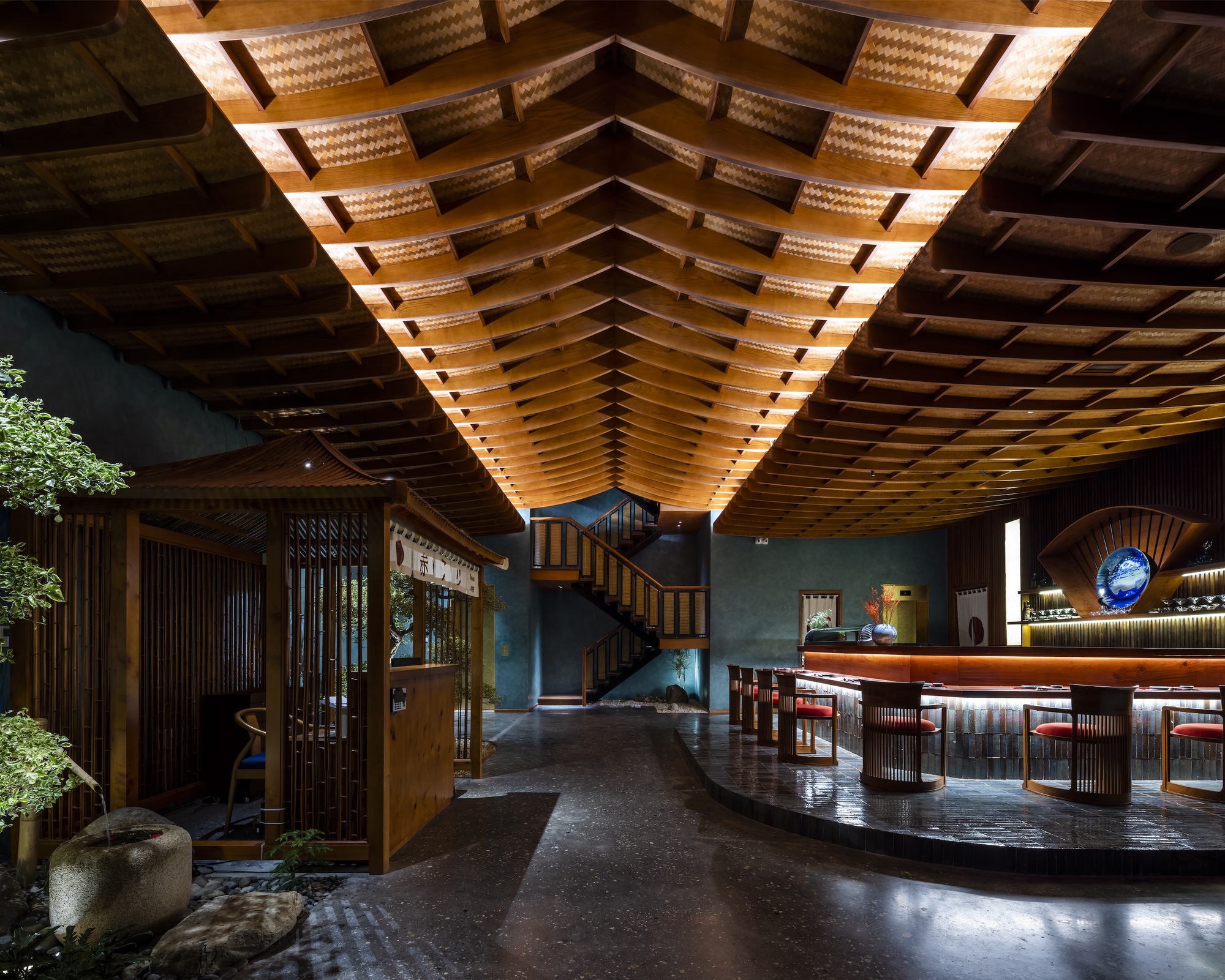 Double-height lobby showing the vaulted wood-slat ceiling with integrated lighting above a central interior garden