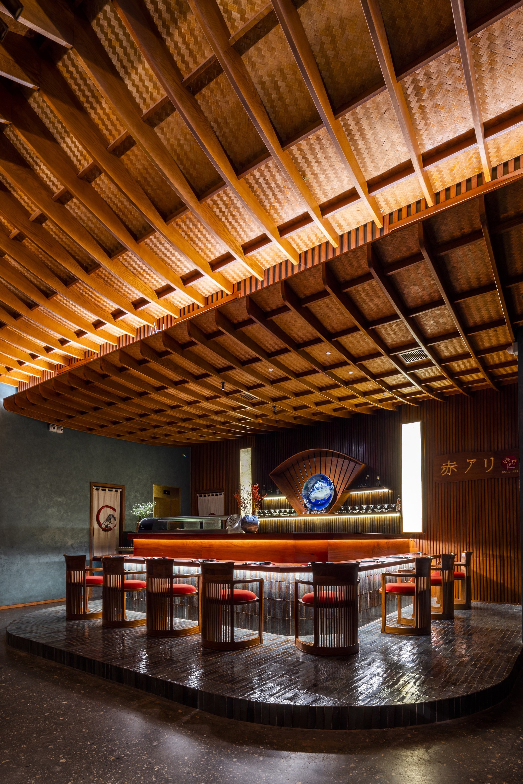 Dining area with woven bamboo coffered ceiling above circular platform and timber counter with stools