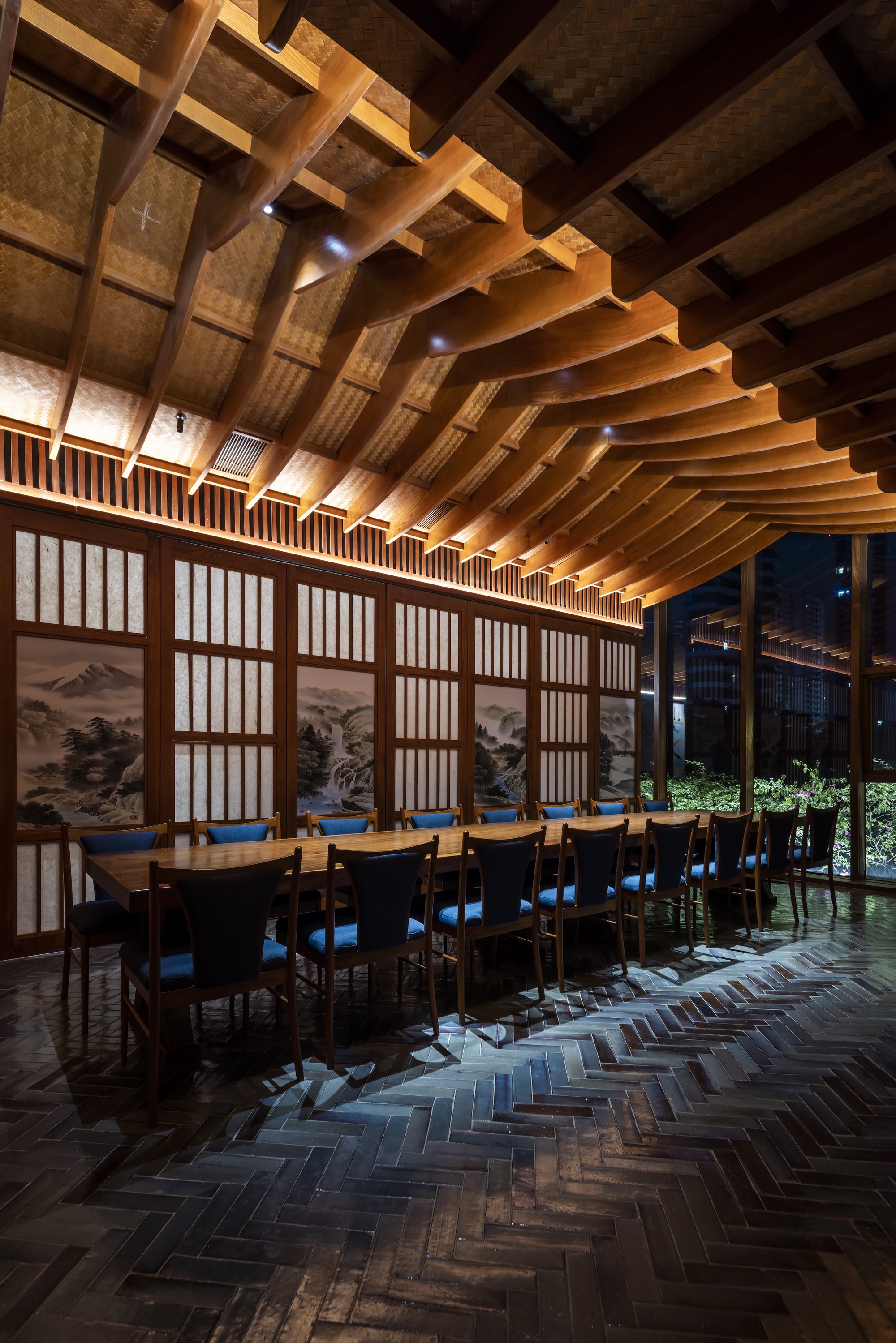 Dining hall with curved timber beam ceiling and translucent shoji screens along one wall at night