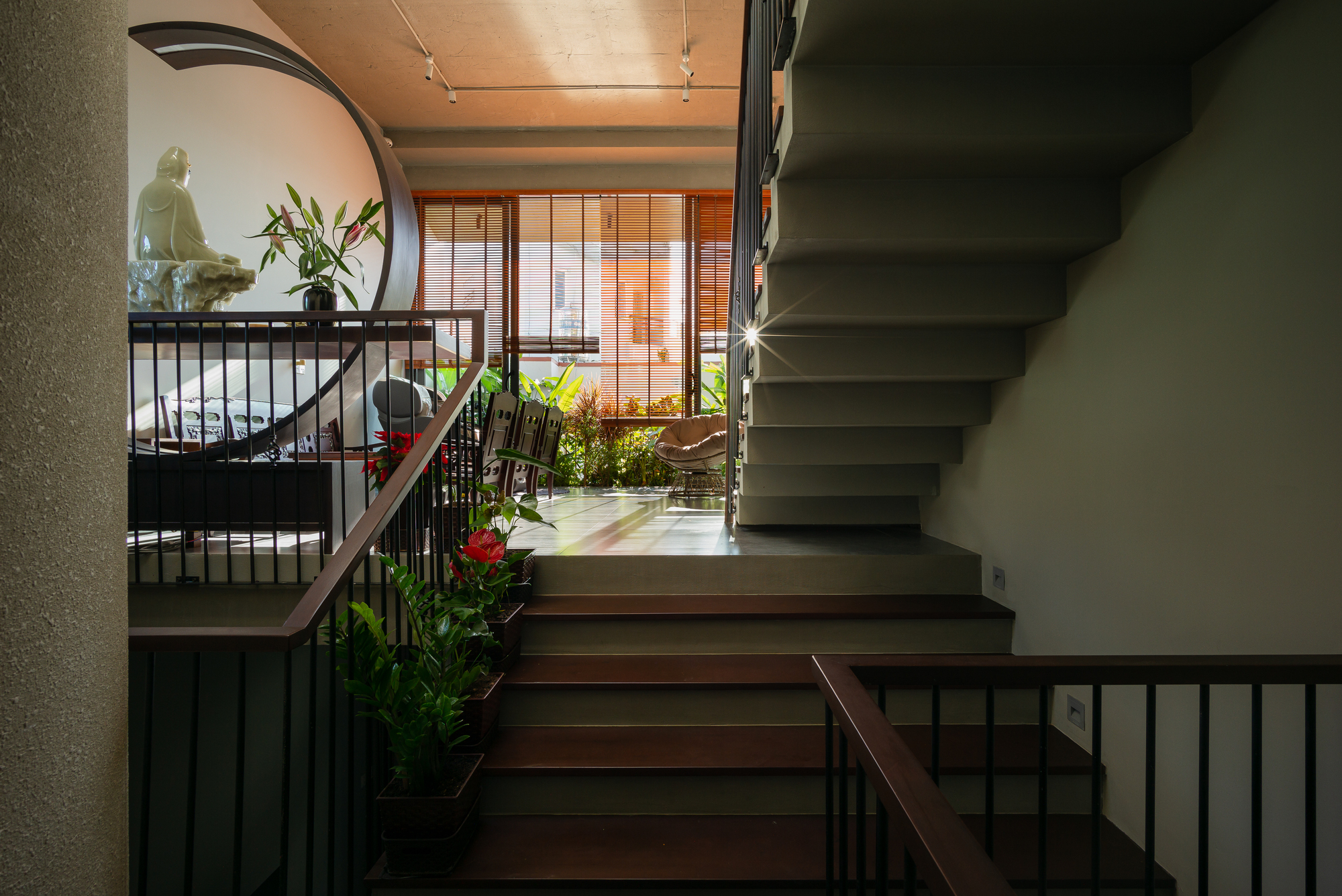 Staircase landing with timber treads and metal railings overlooking planted upper-level terraces
