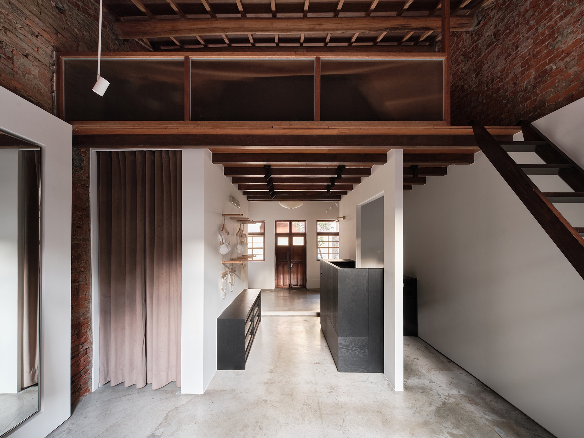 Double-height space with mezzanine stair, exposed brick walls, and timber ceiling structure with clerestory windows