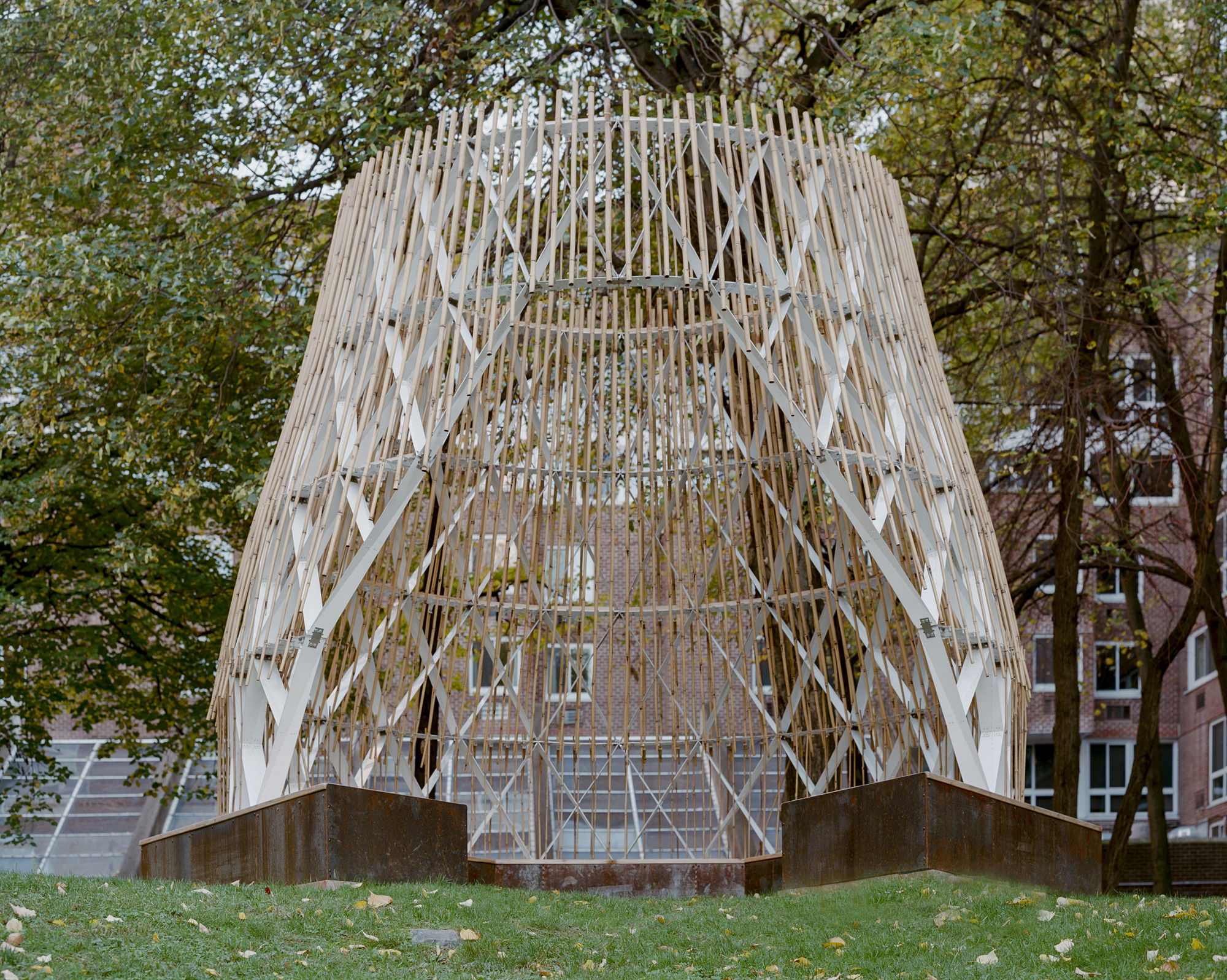 Close view of the lattice pavilion facade showing diagonal timber members and vertical slats against brick buildings