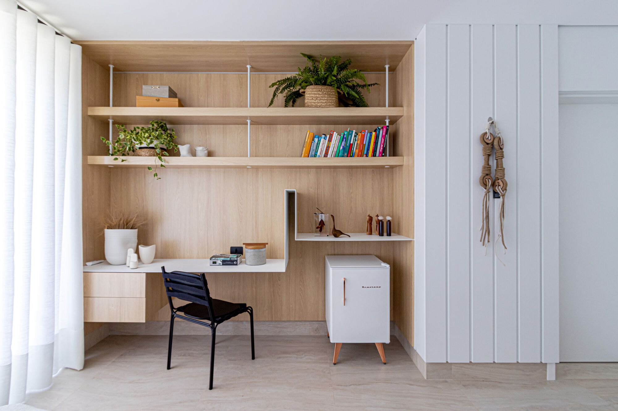 Recessed workspace niche with timber shelving and white cabinetry beside a vertical slat partition