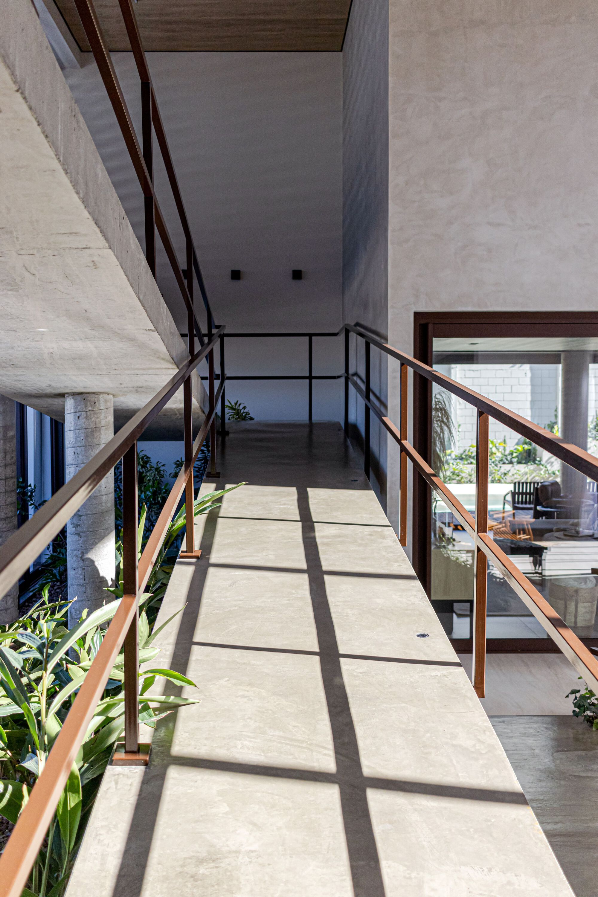 Concrete bridge with timber and steel railings casting shadows across the floor from overhead skylights