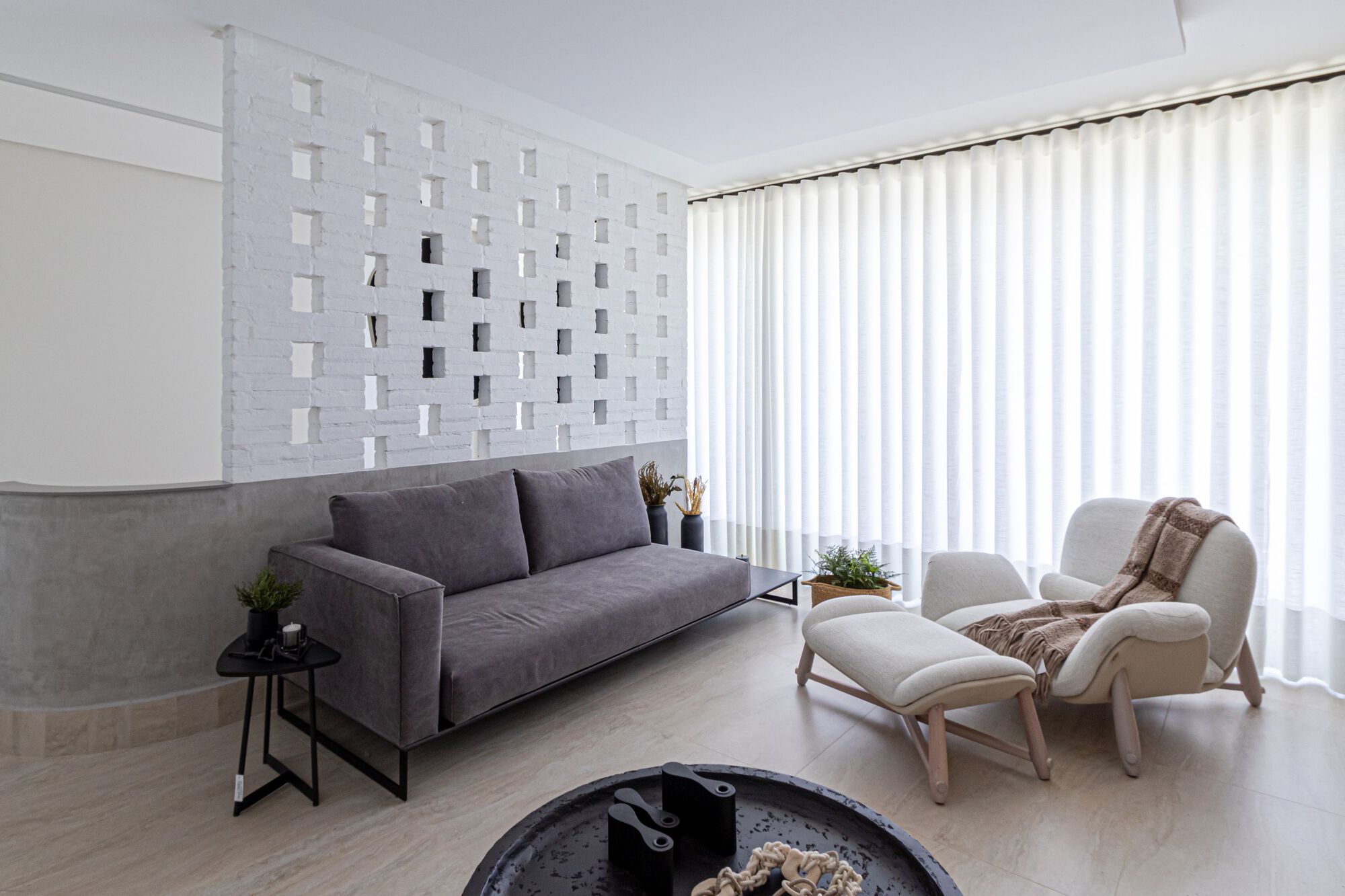 Living room with perforated white brick screen wall and full-height curtains filtering natural light