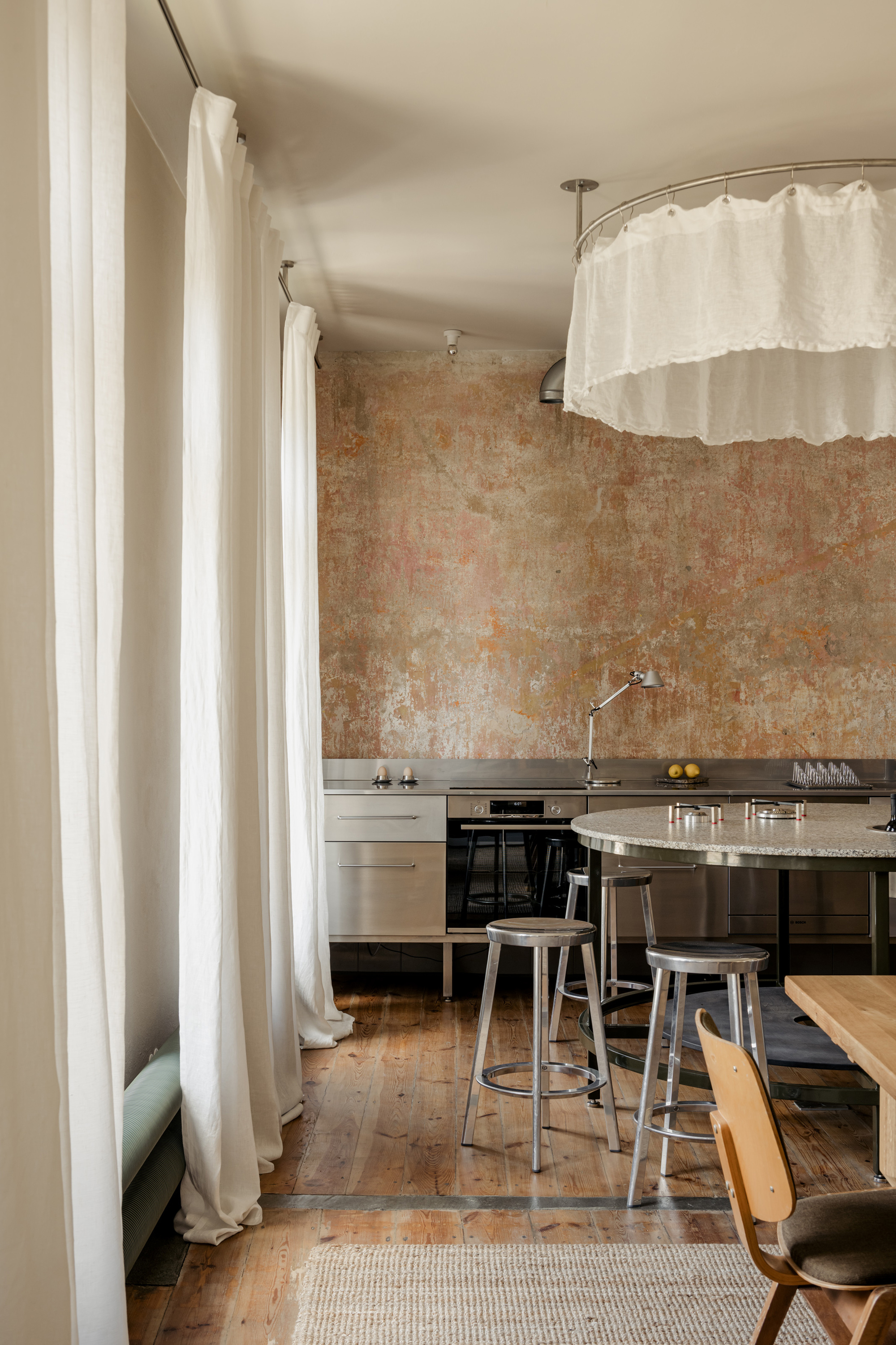 Kitchen with weathered plaster wall, white fabric curtain dividers and reclaimed timber floorboards