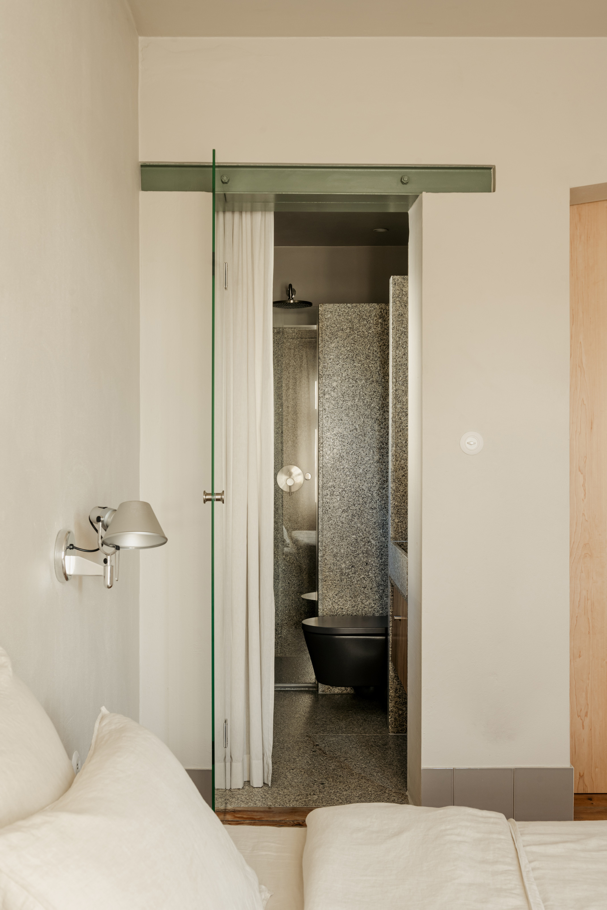 Bedroom view through doorway into bathroom with terrazzo flooring and freestanding black tub