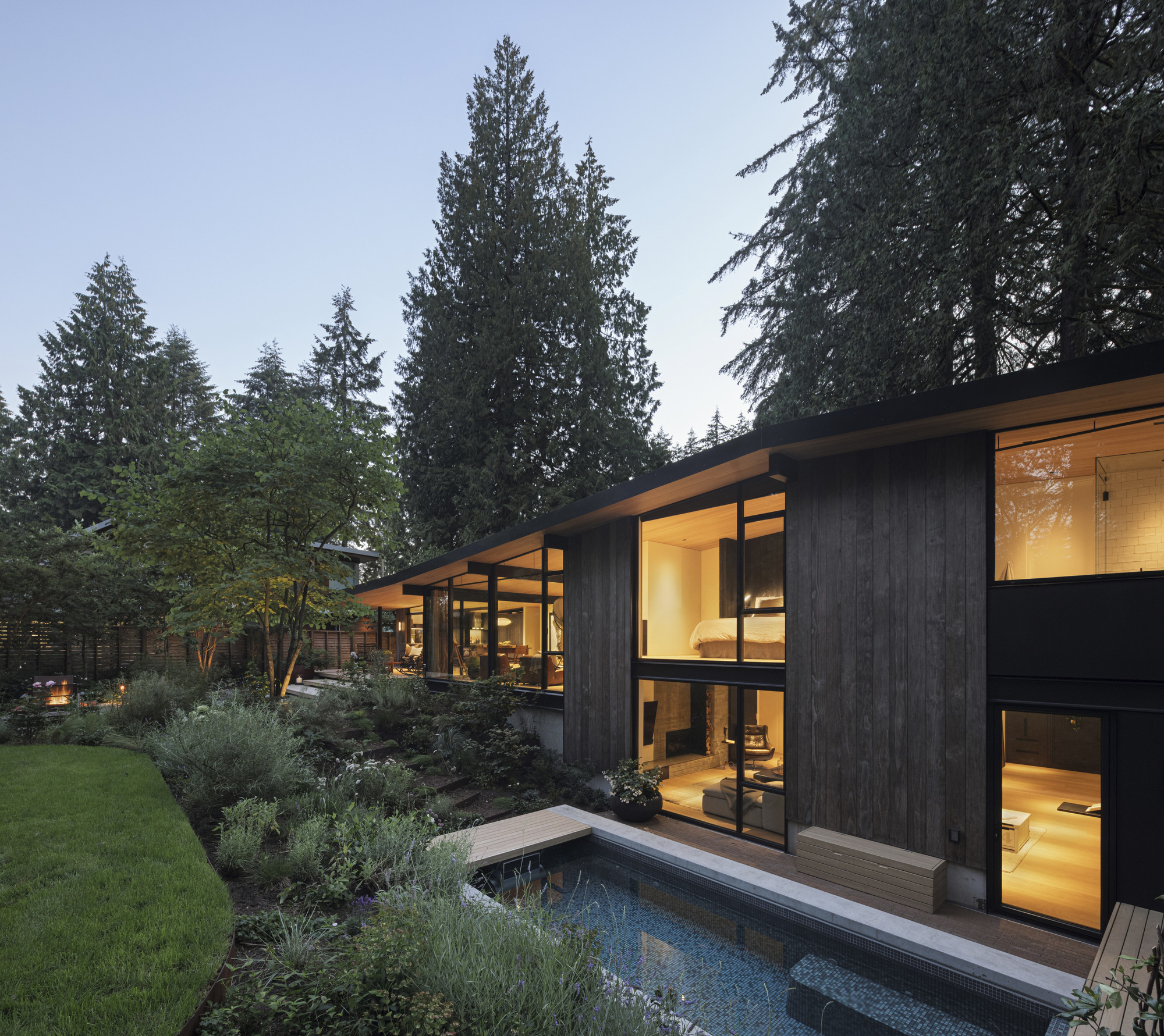 Rear facade with lap pool and planted terraces beneath a darkening sky