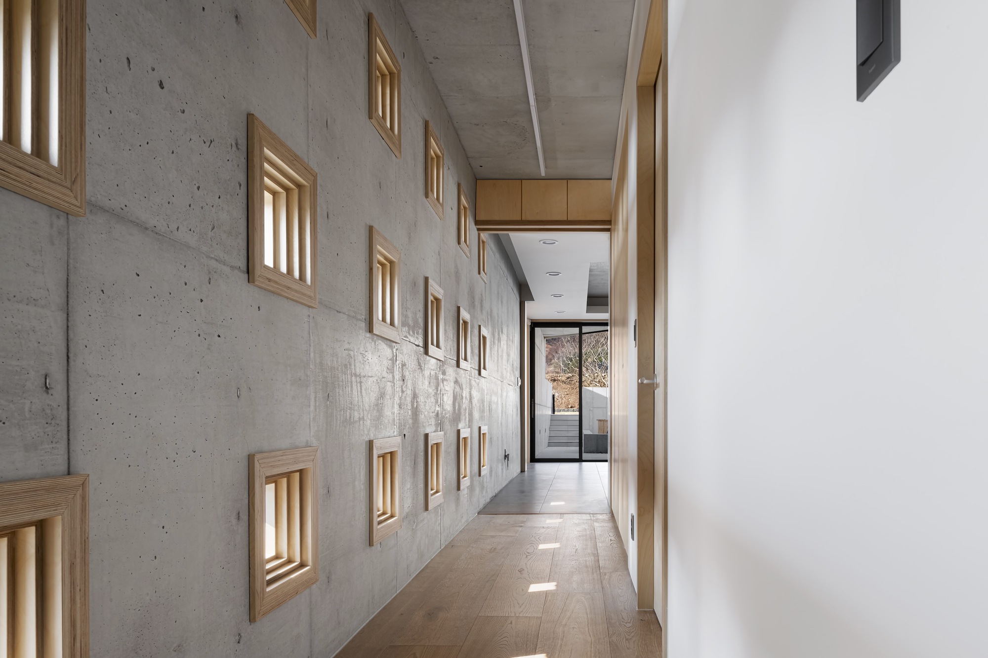 Corridor with timber-framed niches in board-formed concrete wall under exposed ceiling soffit