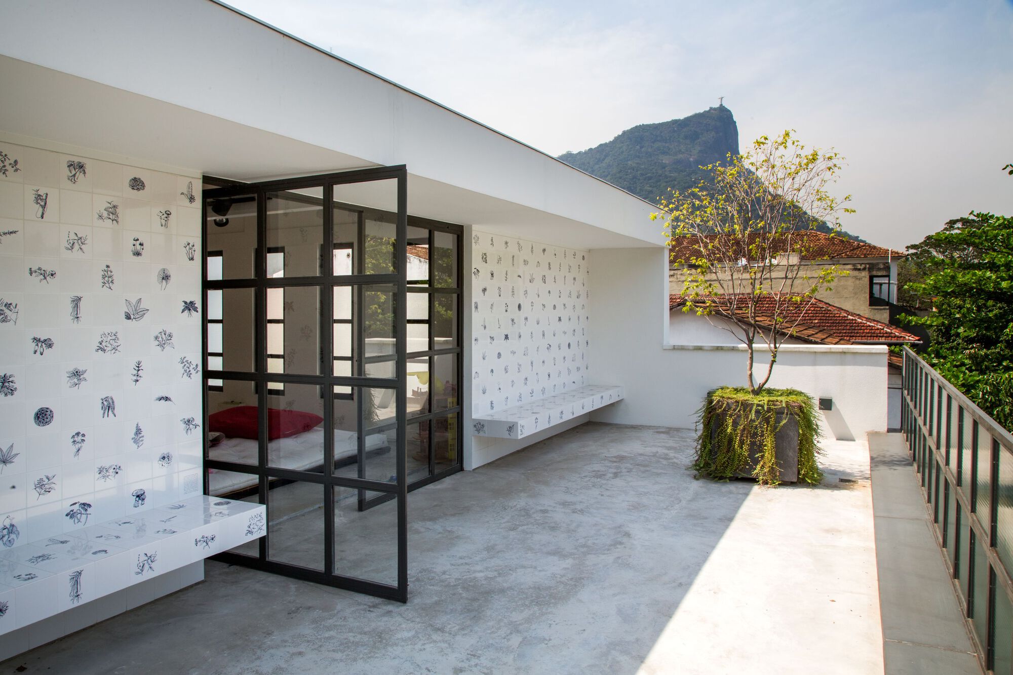 Concrete terrace with black steel framed glass doors opening to a bedroom beneath a distant mountain peak