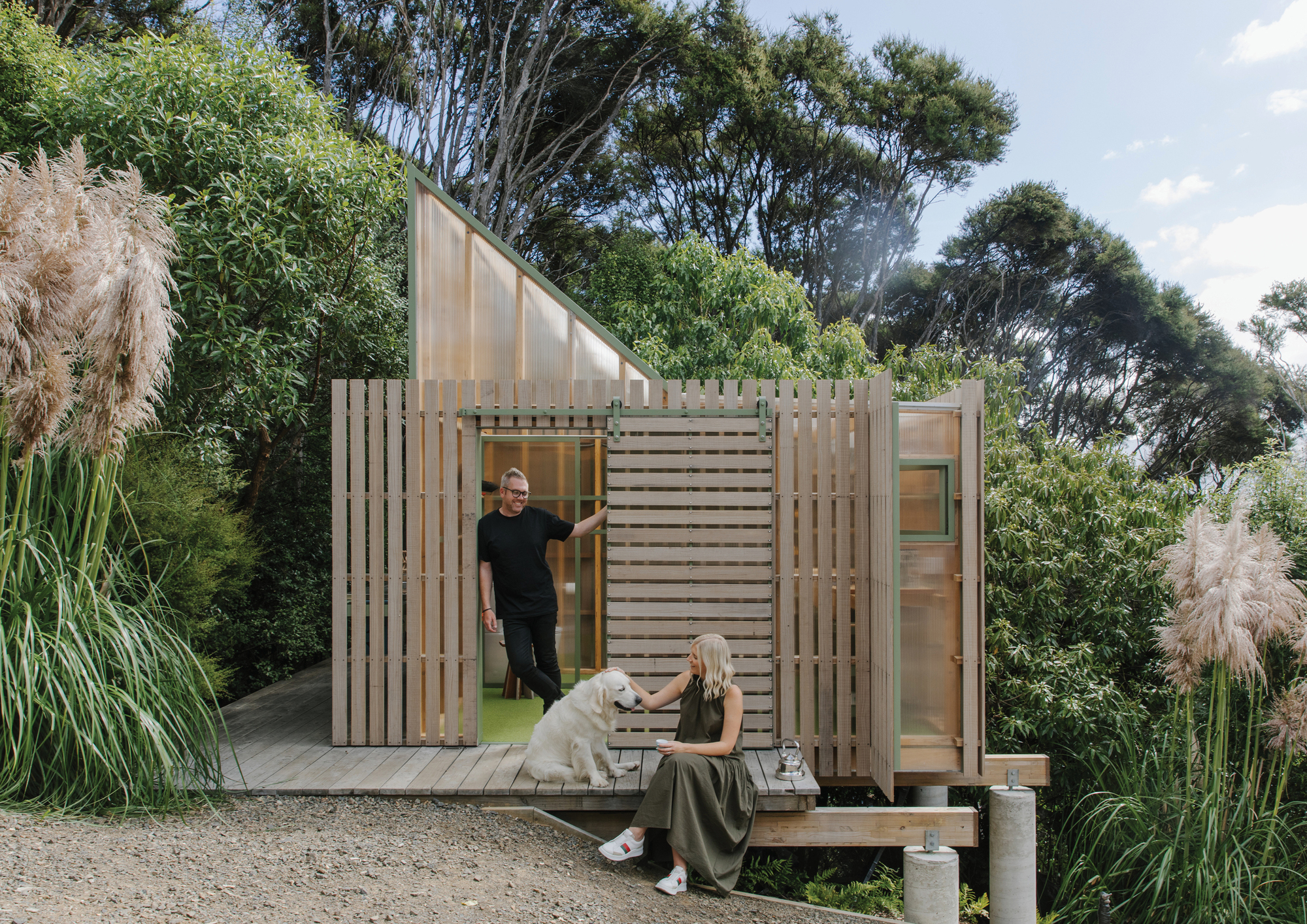 Timber slat facade with translucent polycarbonate panels and sliding doors, two people on the deck