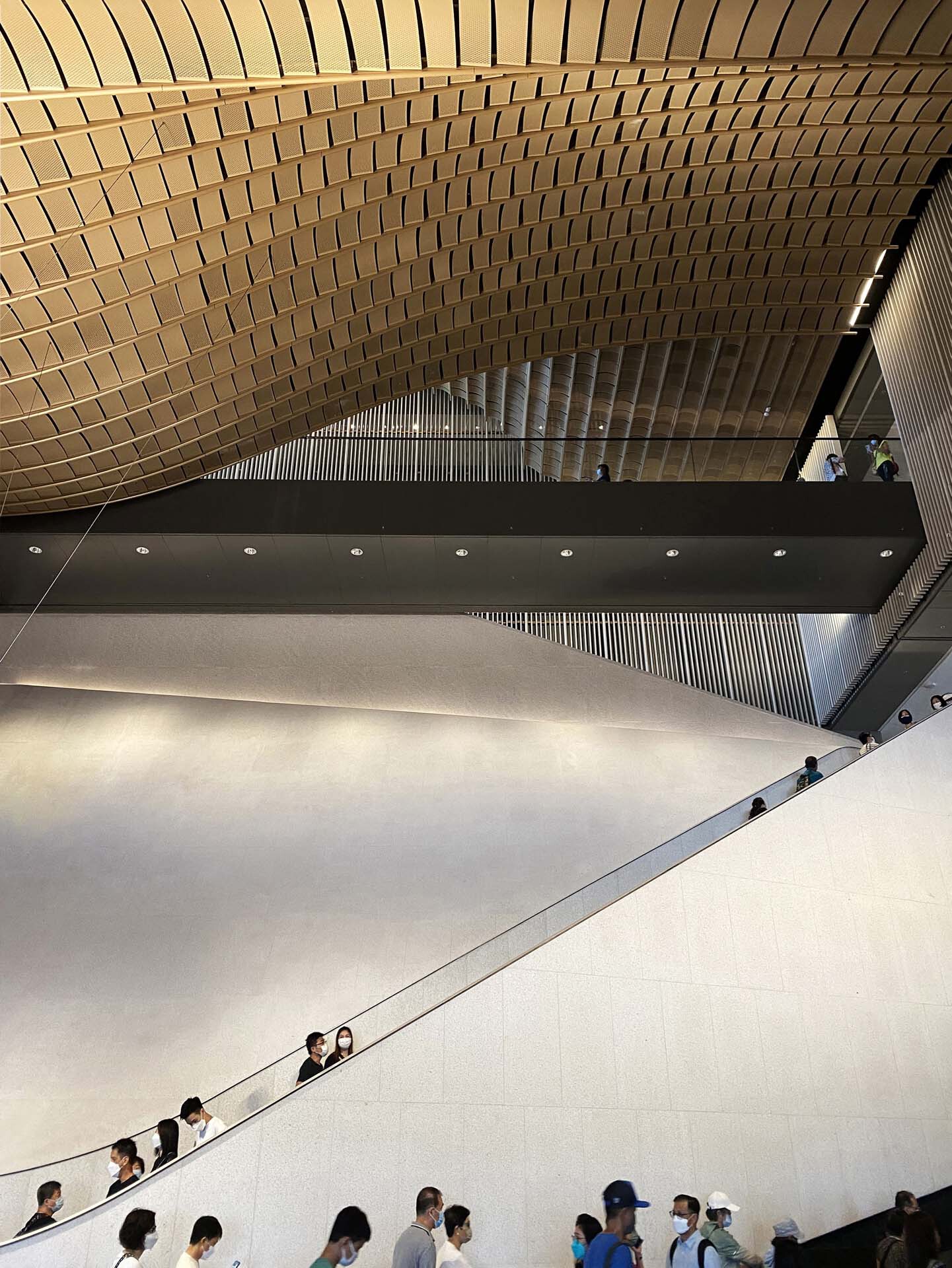 Overhead view of the white sloped wall with visitors ascending the adjacent staircase