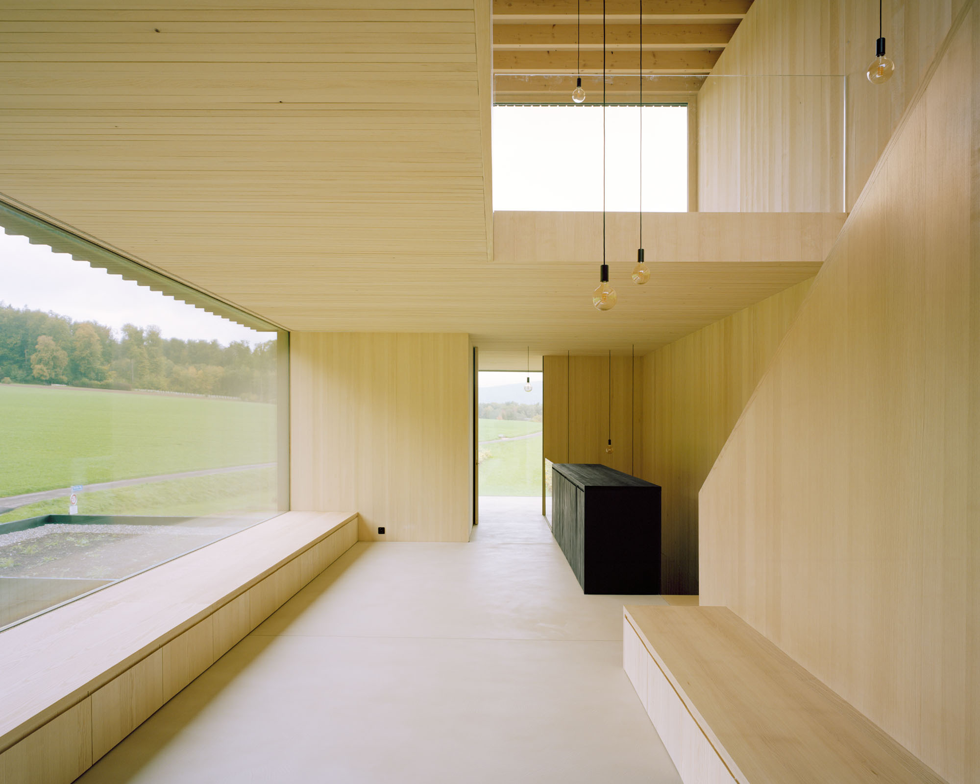 Open living space with clerestory and suspended pendant lights above the dark cabinet island