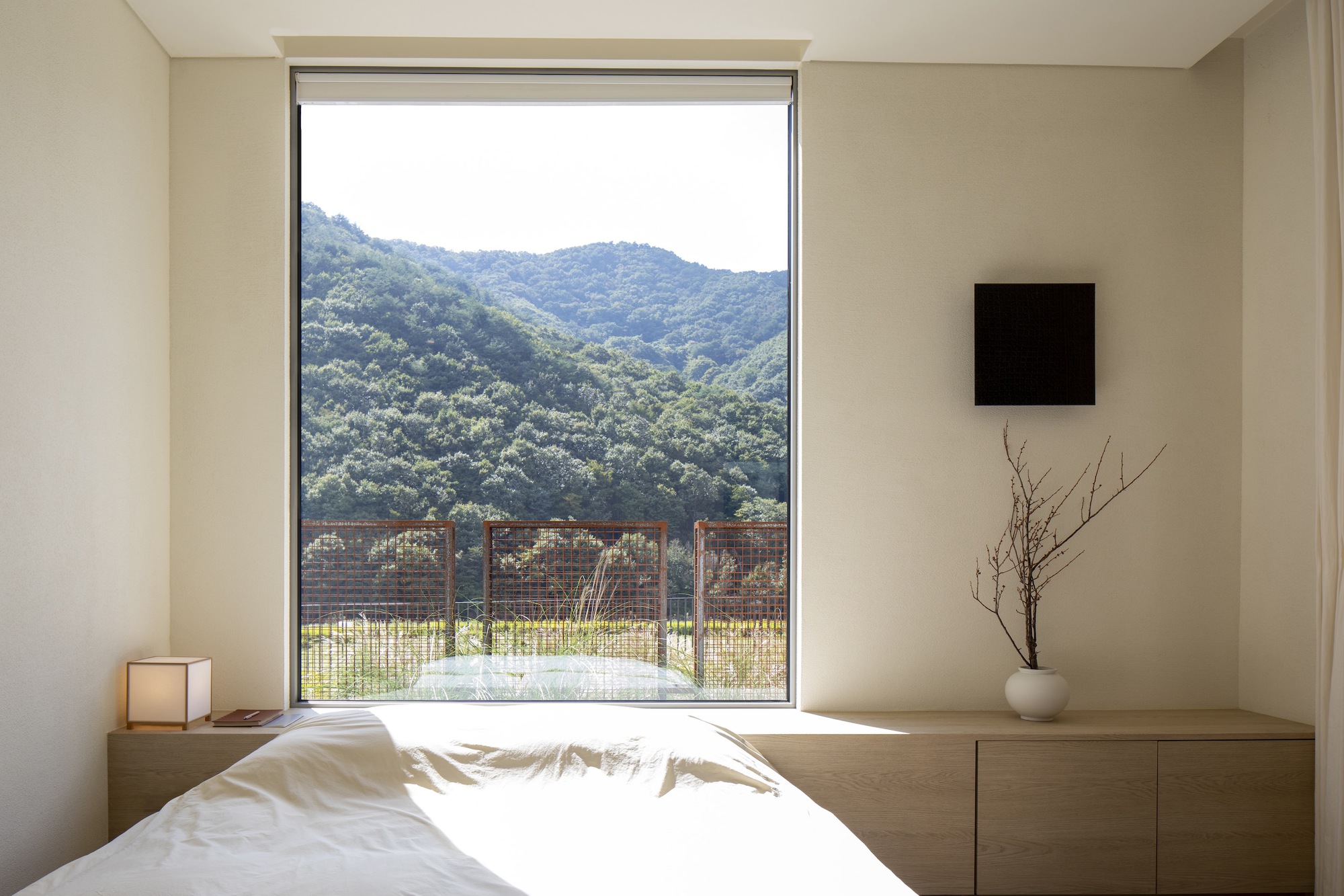 Bedroom with picture window framing mountain view and wire mesh balcony railing below