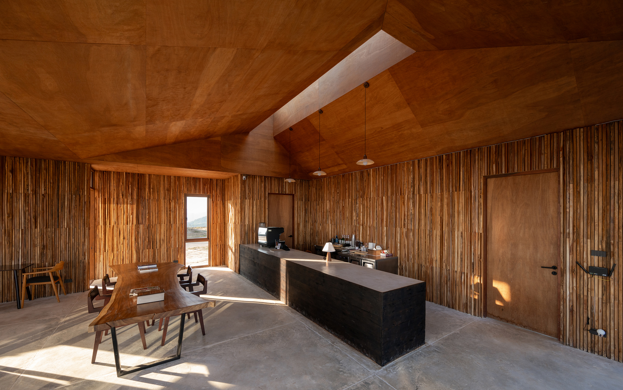 Kitchen and dining area with vertical timber slat walls beneath angular wood ceiling and skylight