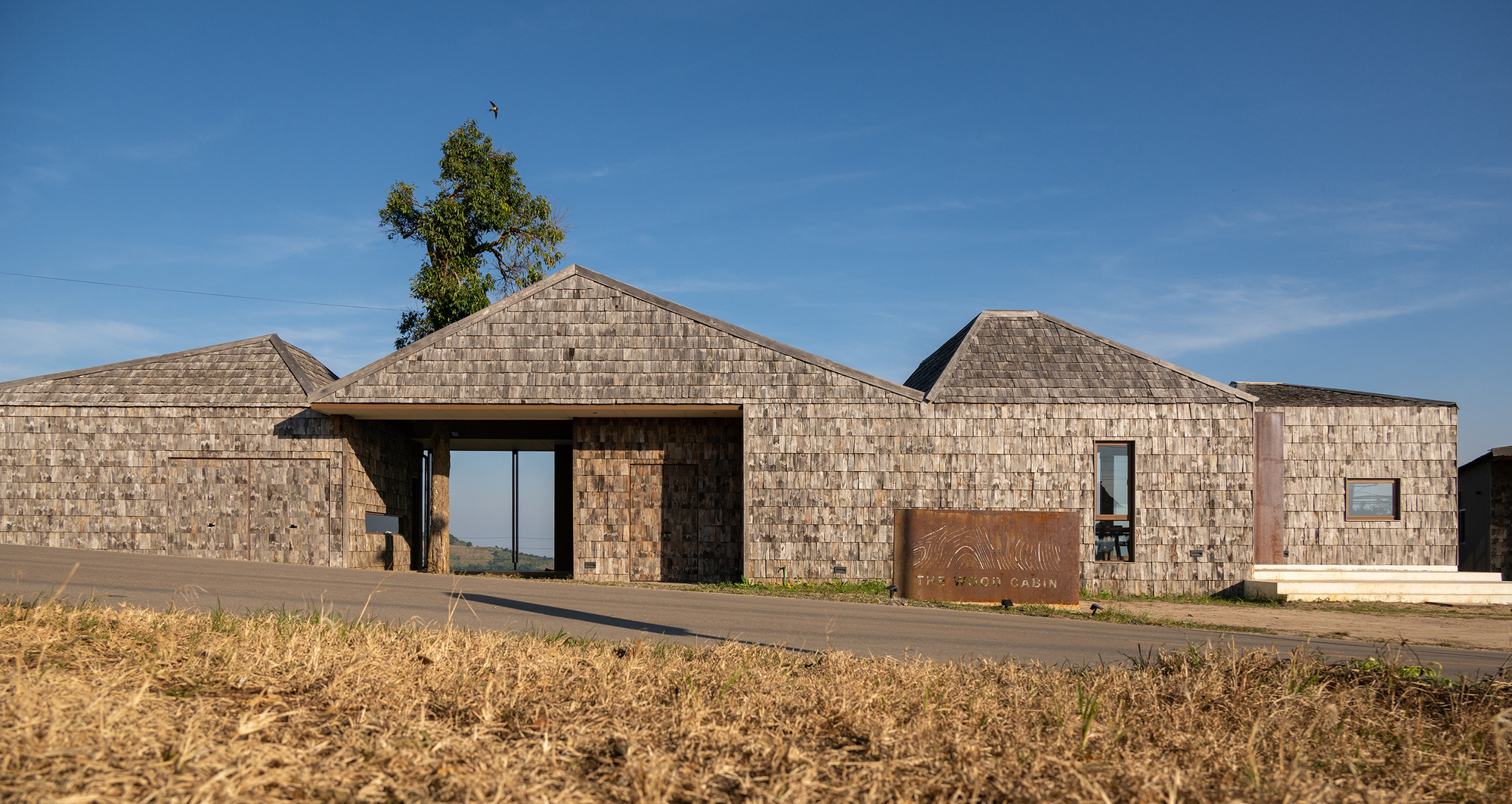 Front elevation showing clustered gabled volumes clad in textured stone with a tree emerging from one roof