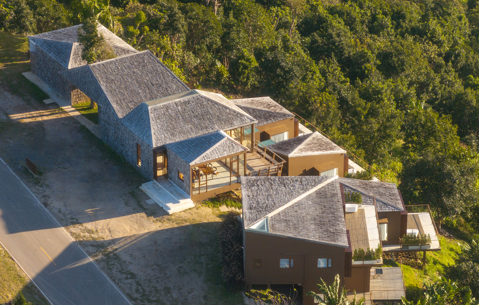 Aerial view of the compound with multiple peaked roofs scattered among green lawn and wooded edges