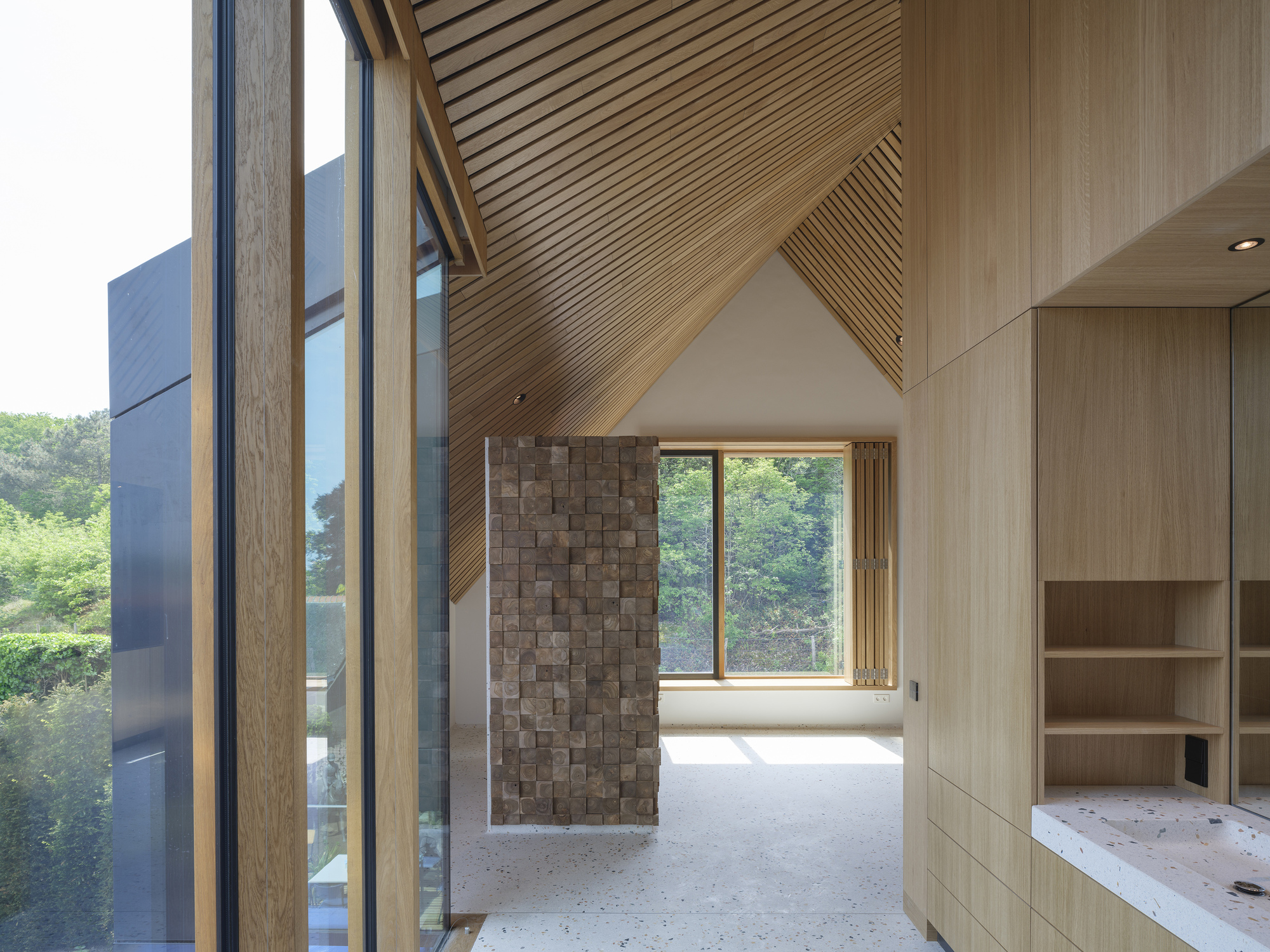 Interior with diagonal timber-slatted ceiling and textured block wall beneath the pitched roof