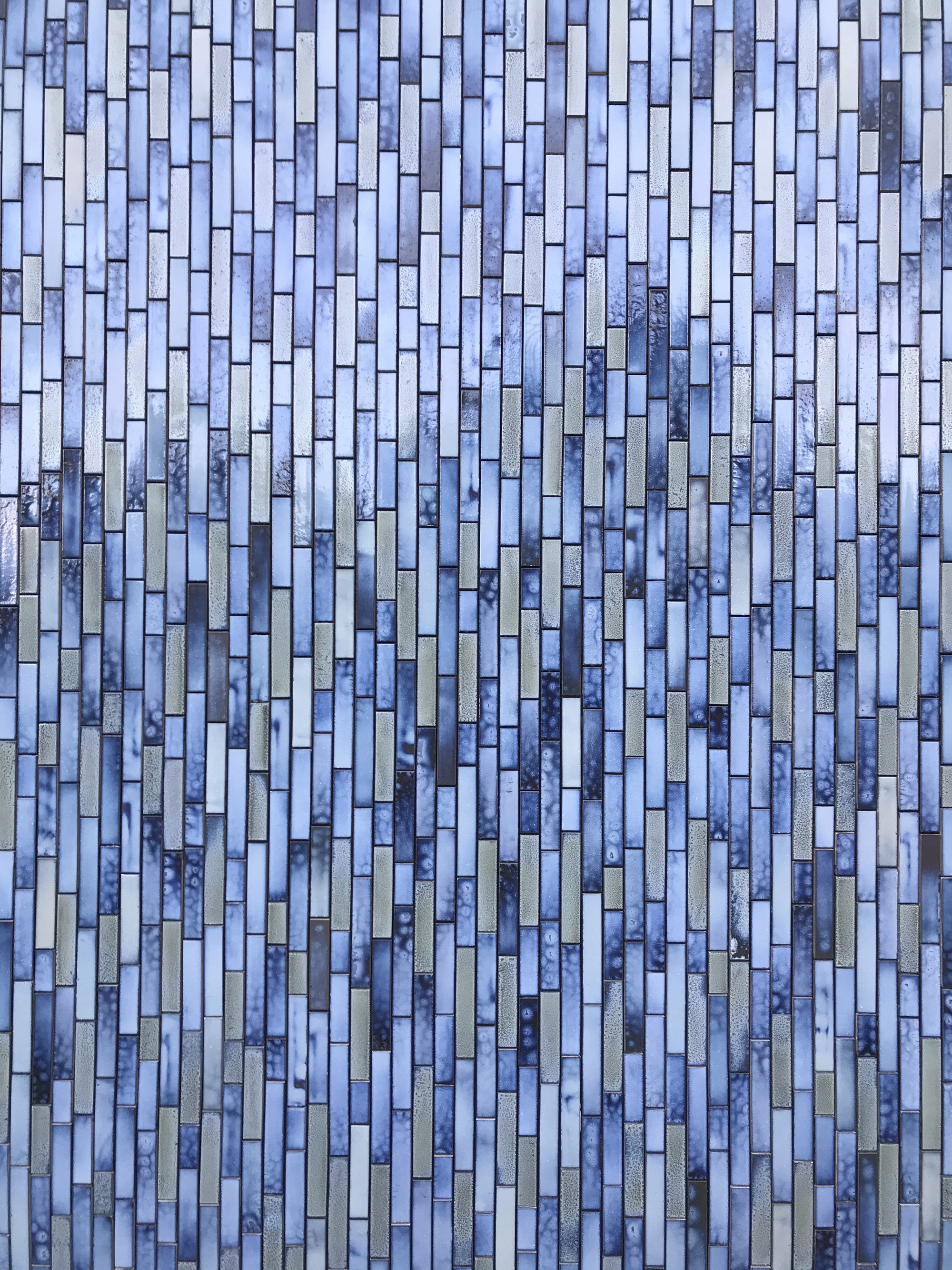 Close-up of the staggered blue and grey glazed tile pattern with varied tones and textures
