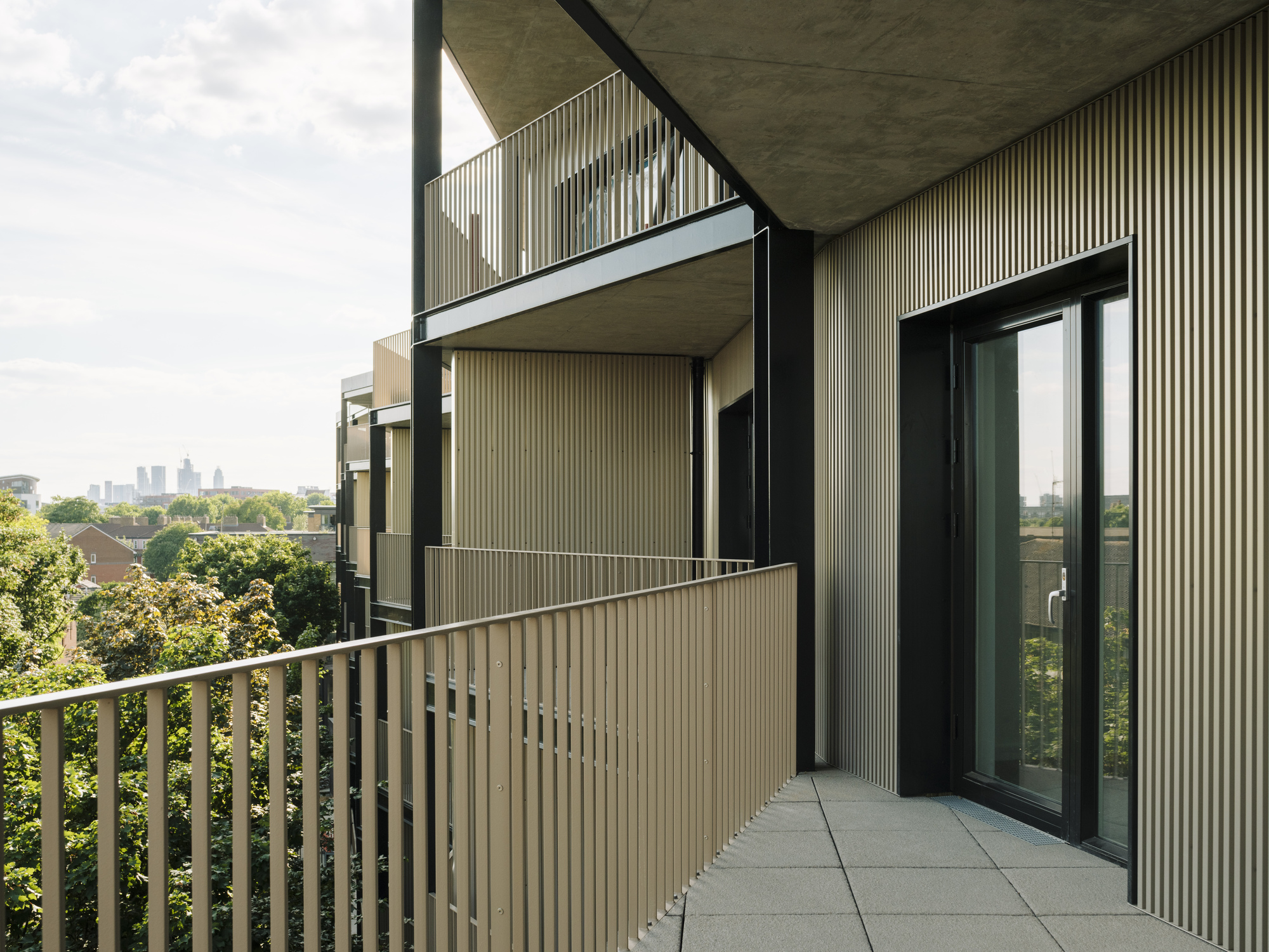 Balcony terrace with vertical metal railings and glazed sliding doors opening to an interior space