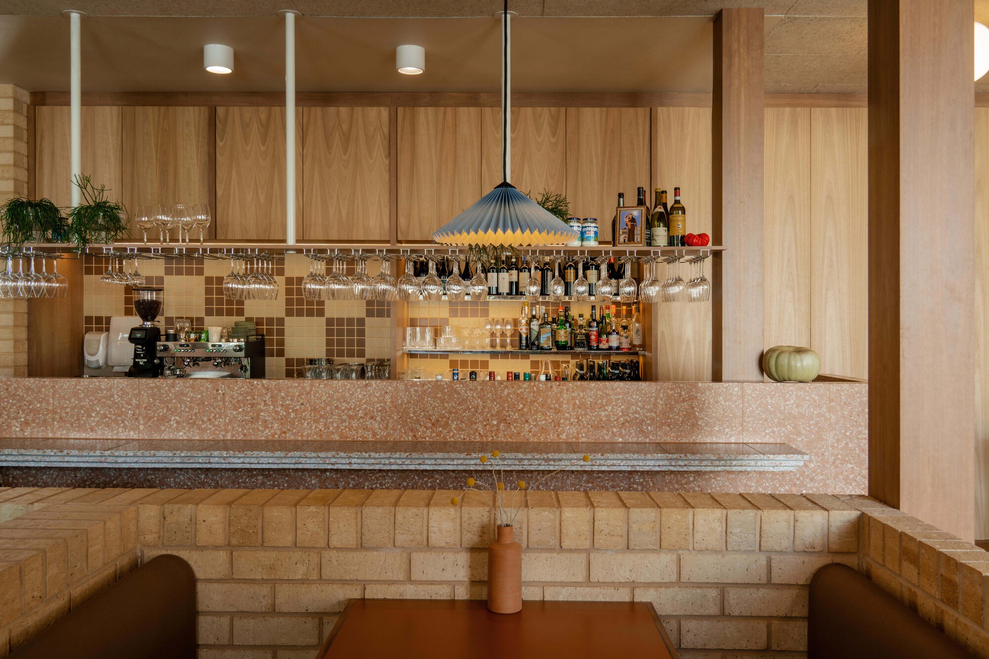 Bar counter with suspended glass rack and mosaic tile backsplash beneath recessed ceiling lights