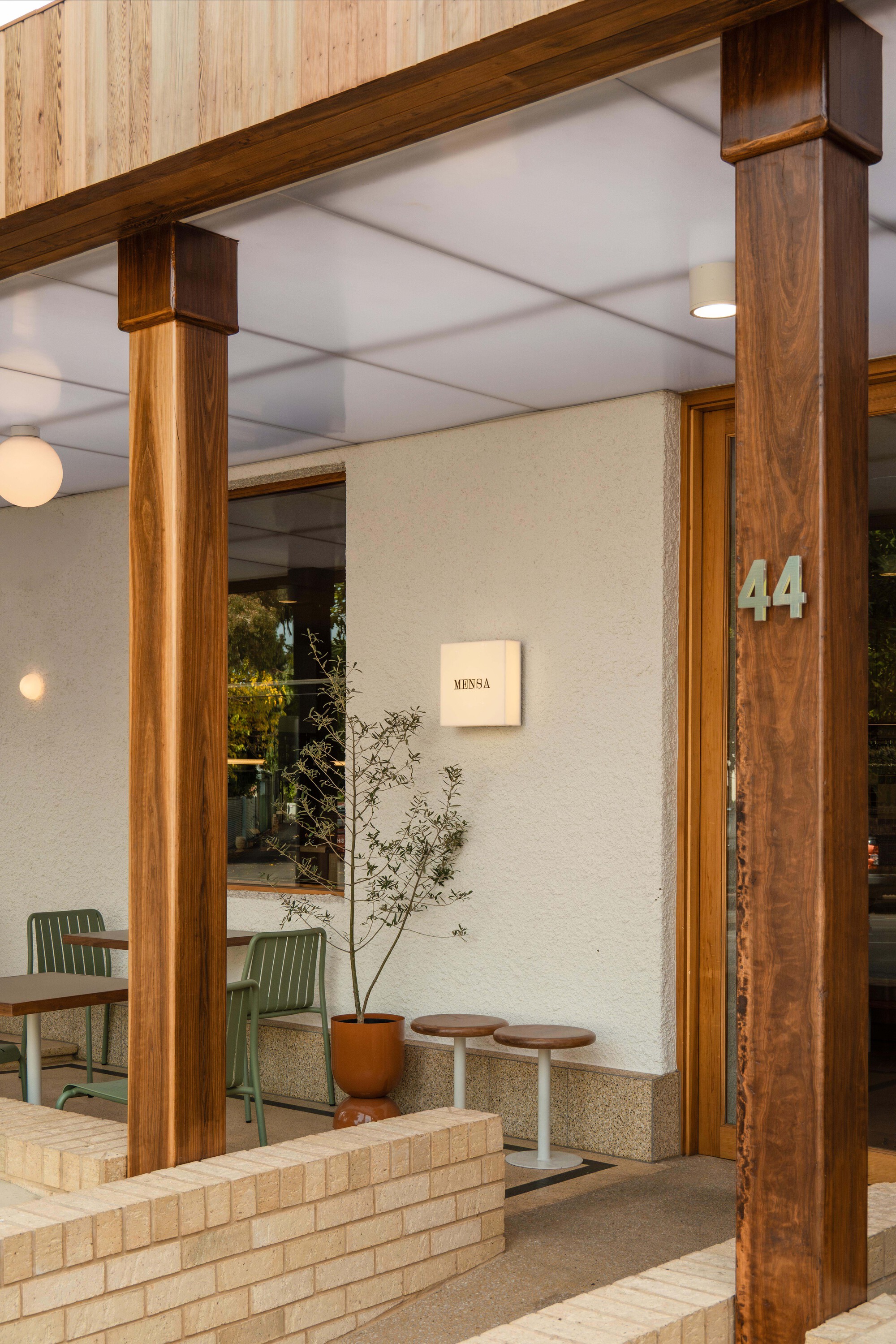 Entrance with timber columns, stucco walls, and a potted plant beside terrazzo flooring