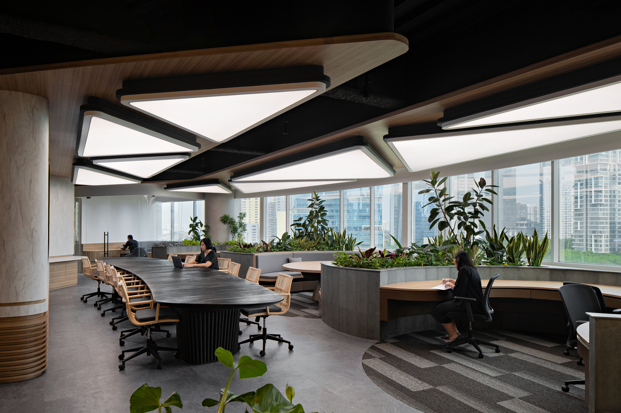 Open workspace showing tiered carpeted platforms leading to curved desks beneath geometric skylights