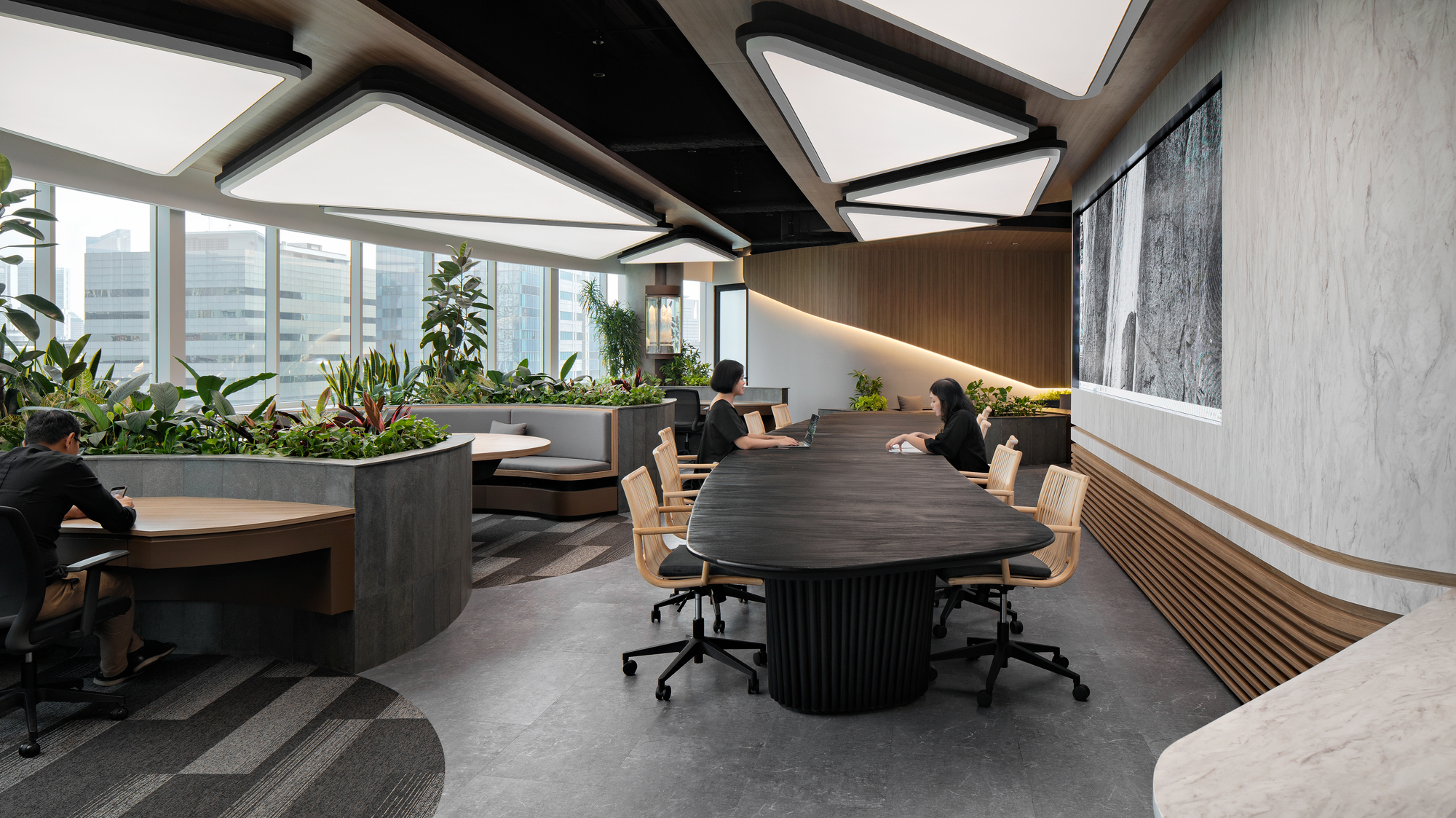 Conference table with fluted black base surrounded by planted beds and timber-clad walls