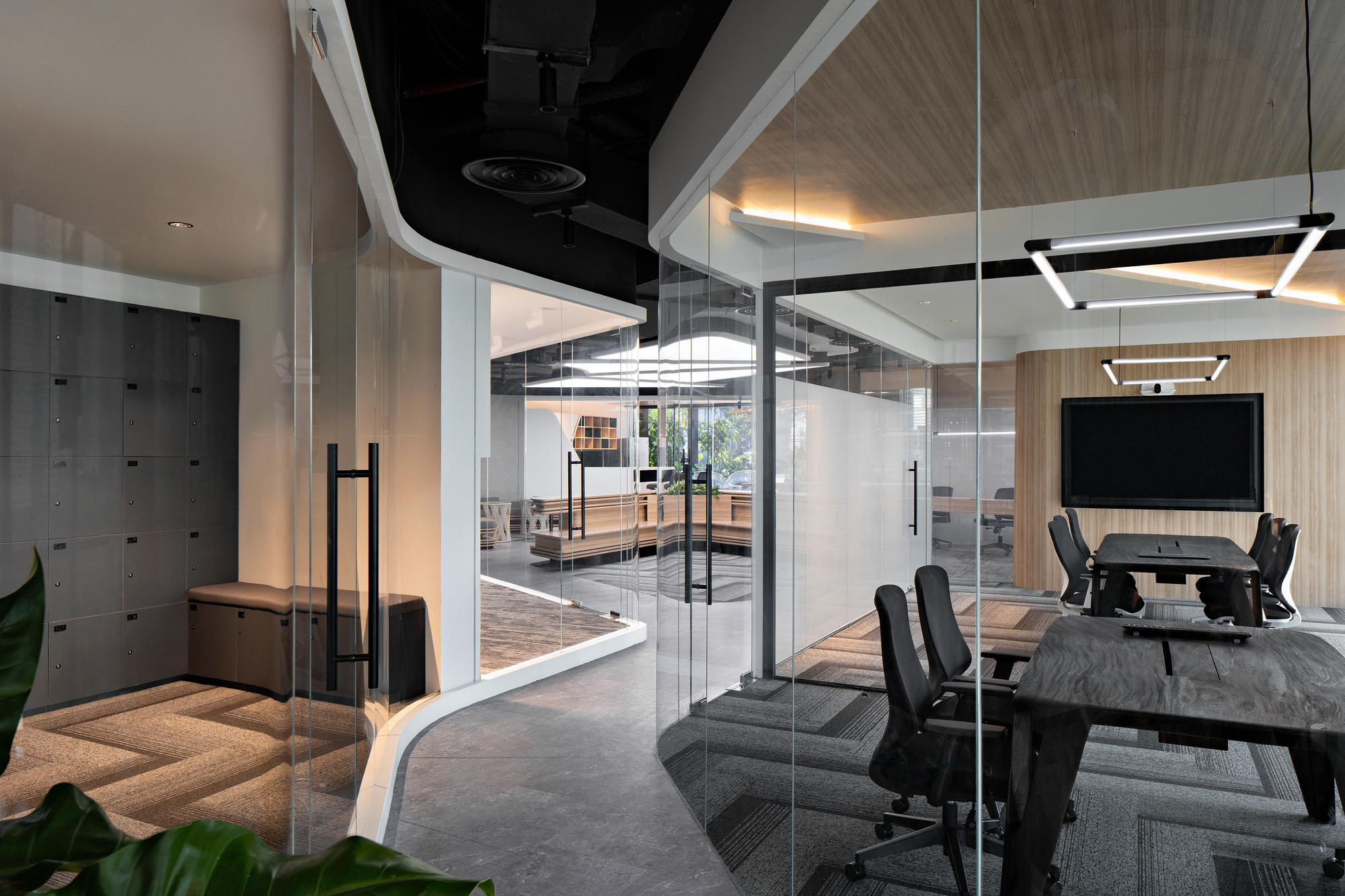 Glass-enclosed meeting rooms with exposed ceiling and locker wall visible through transparent partitions