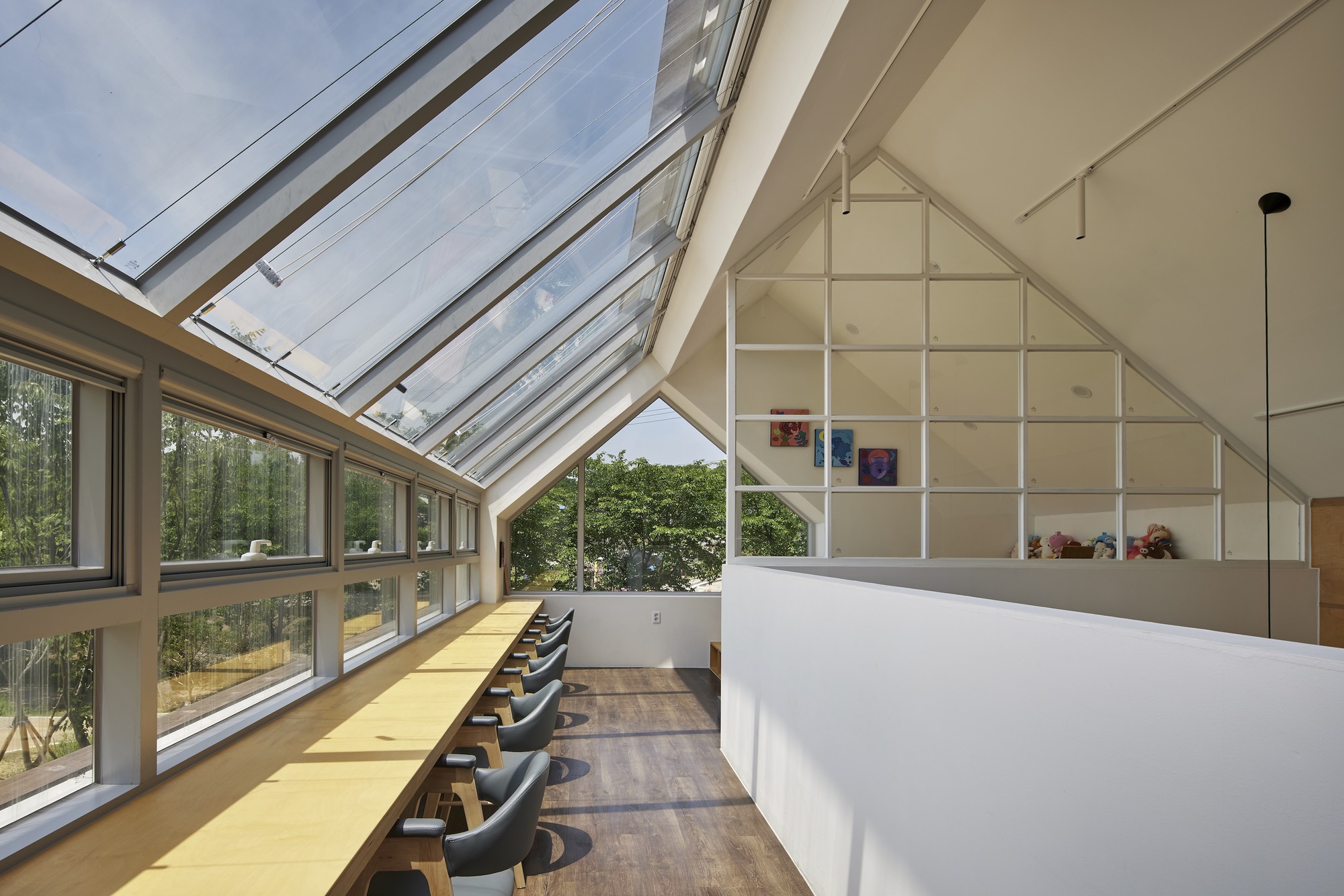 Interior space beneath a glazed pitched roof with yellow counter and built-in shelving