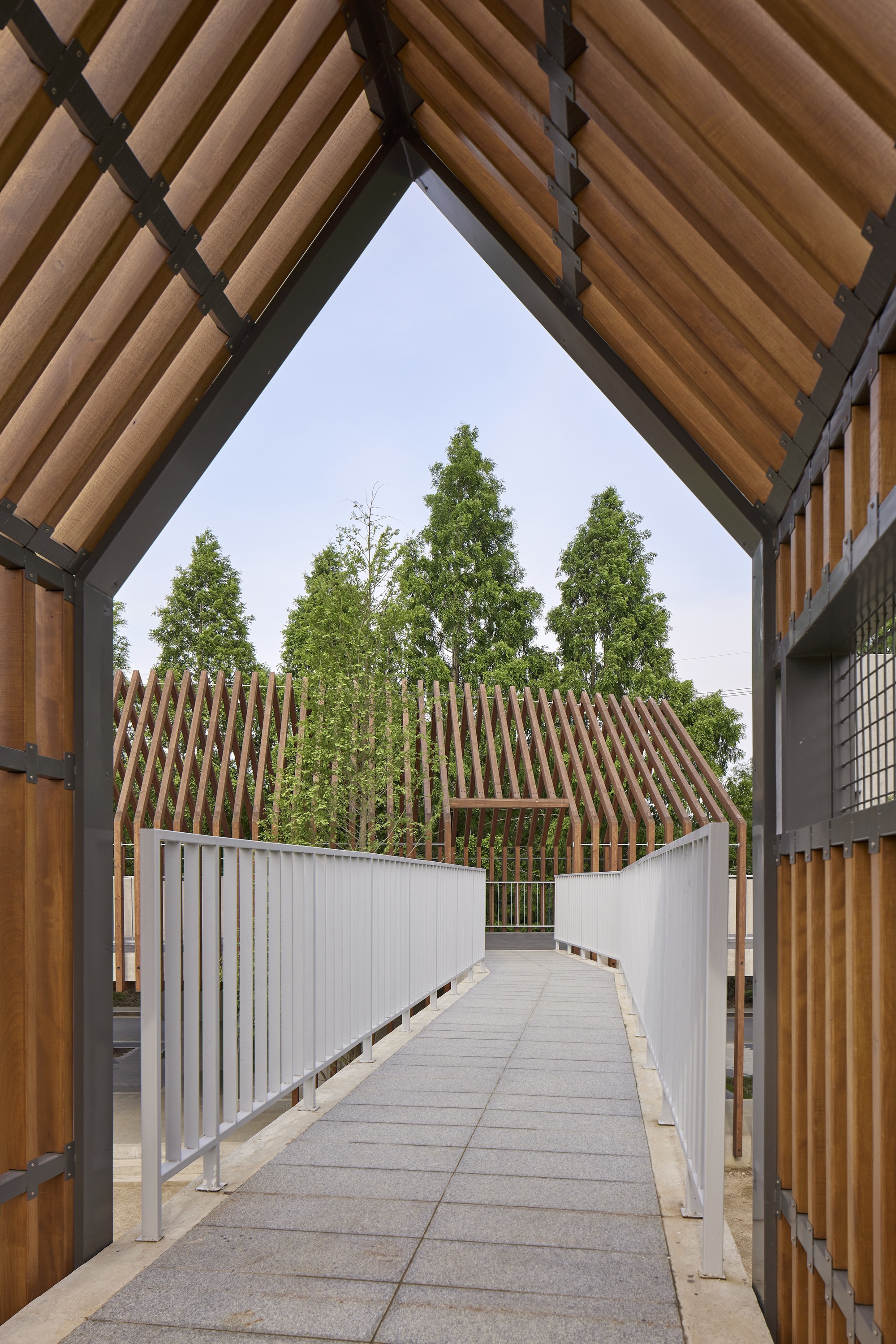 View through timber-framed opening toward the slatted gable structures and connecting bridge