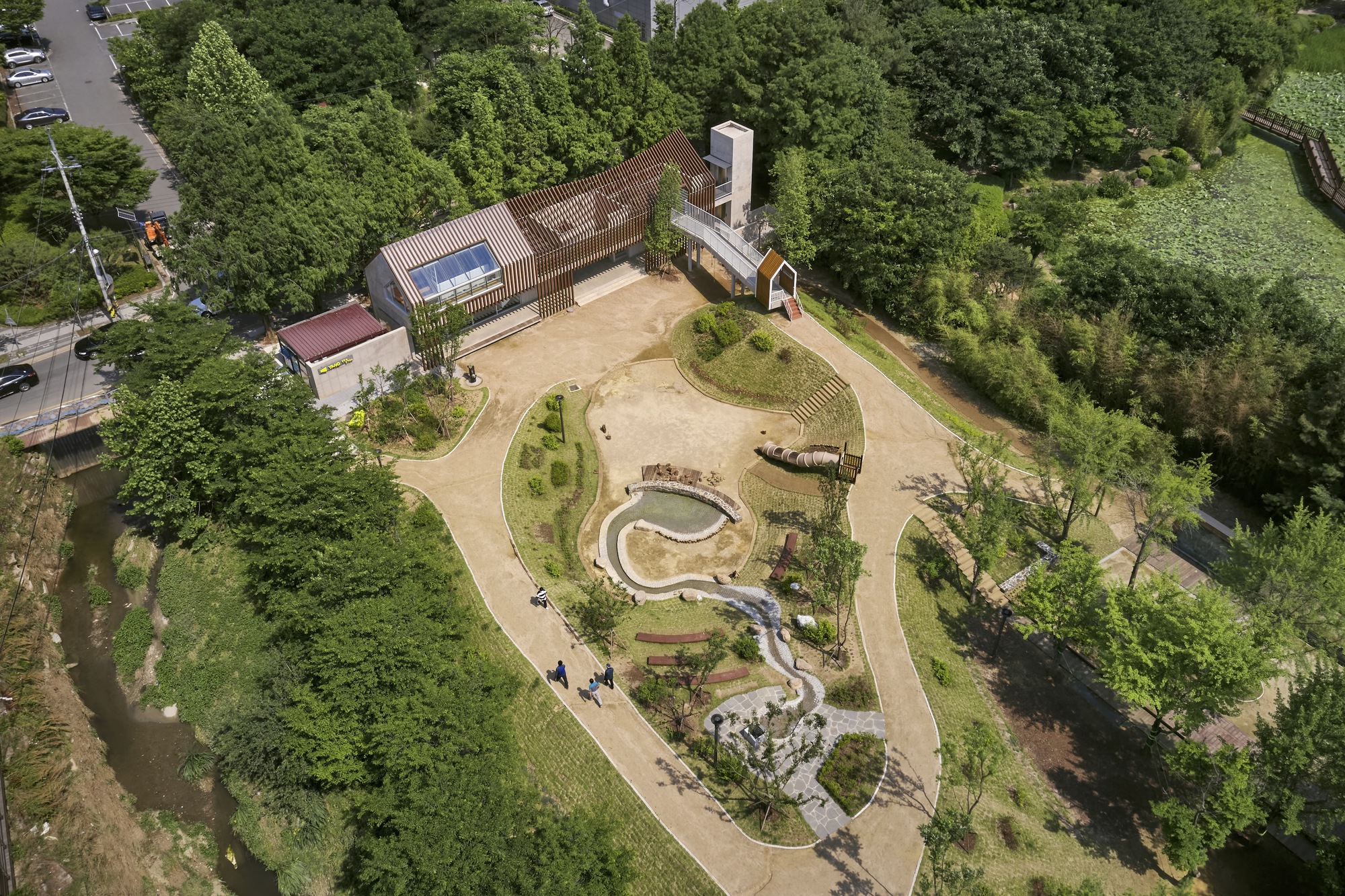 Aerial view of the serpentine water feature and planted mounds surrounded by forest canopy