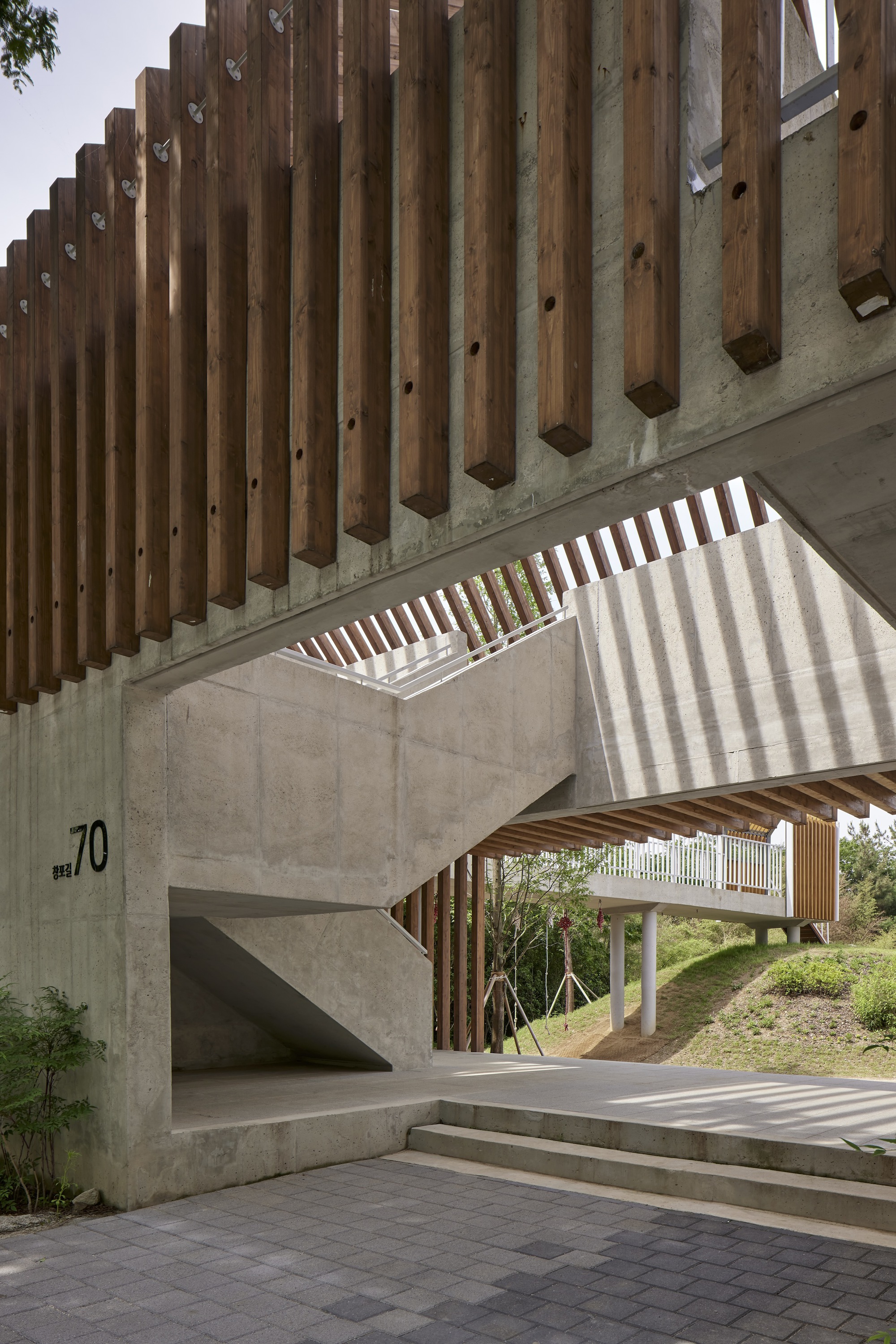 Vertical timber louvers casting stripes of shadow on concrete walls and steps below