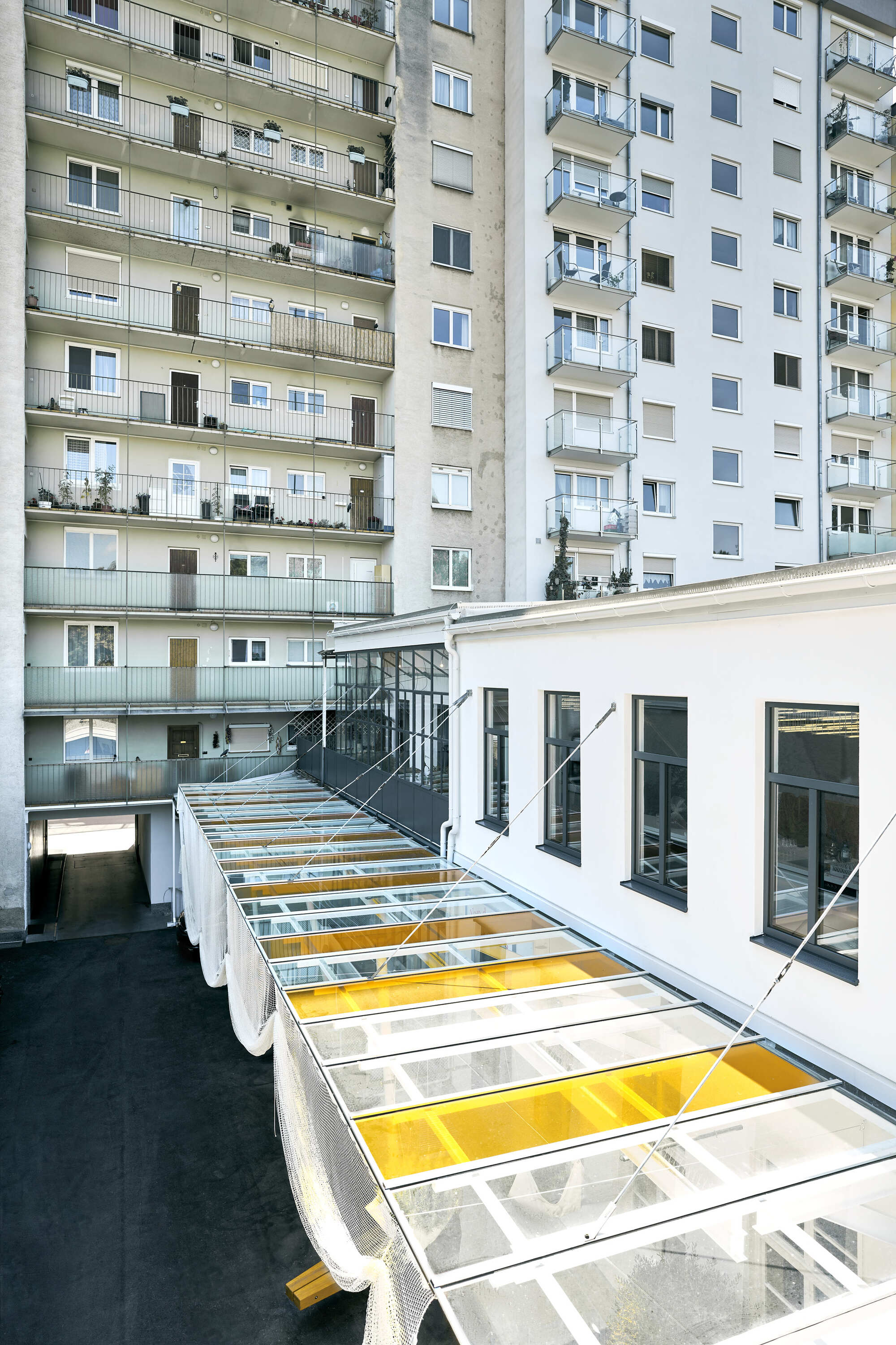 Aerial view of white metal grid roof with clear and yellow glazing panels between residential buildings
