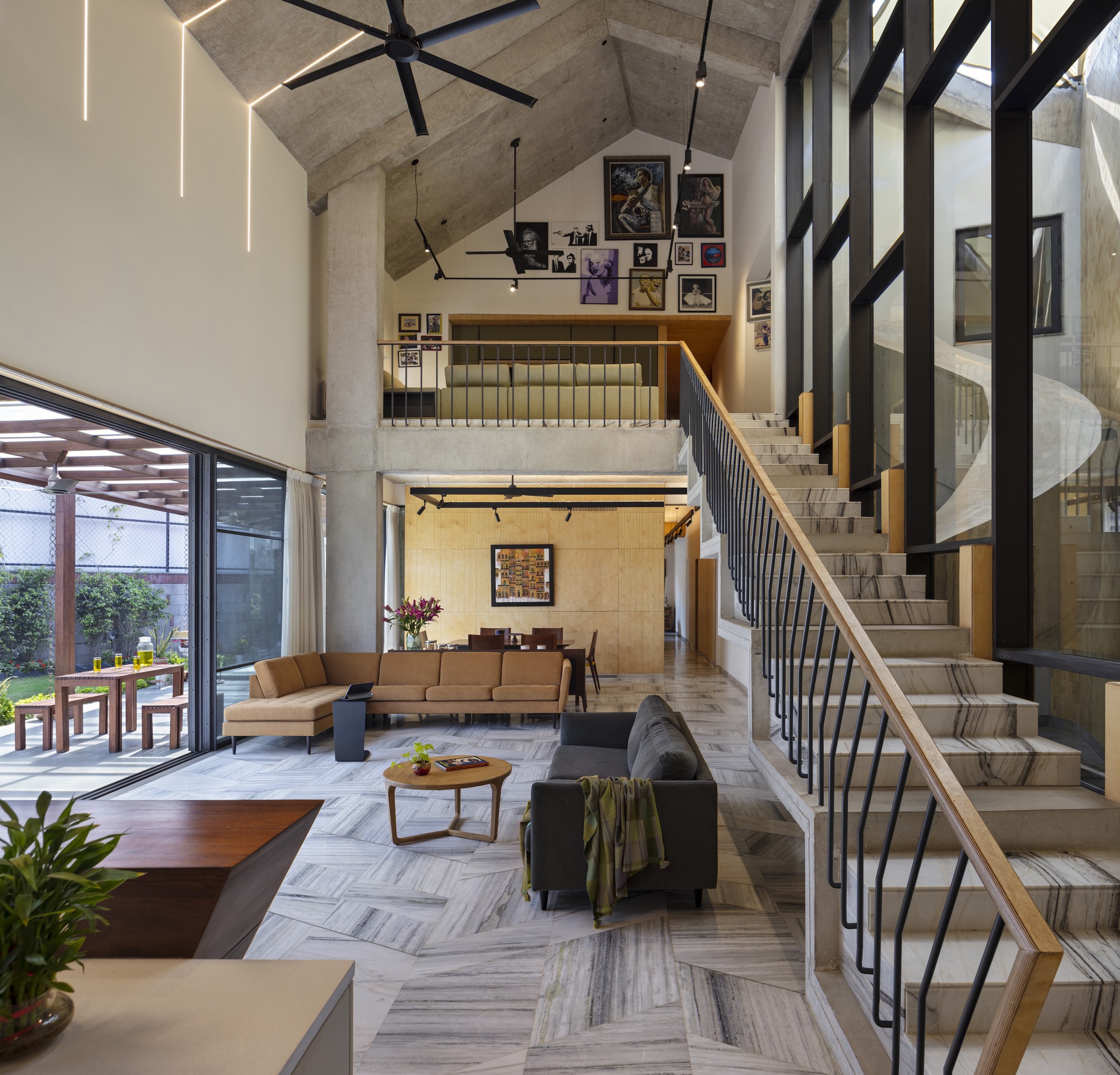 Double-height living room with cantilevered concrete staircase and skylights in the gabled ceiling