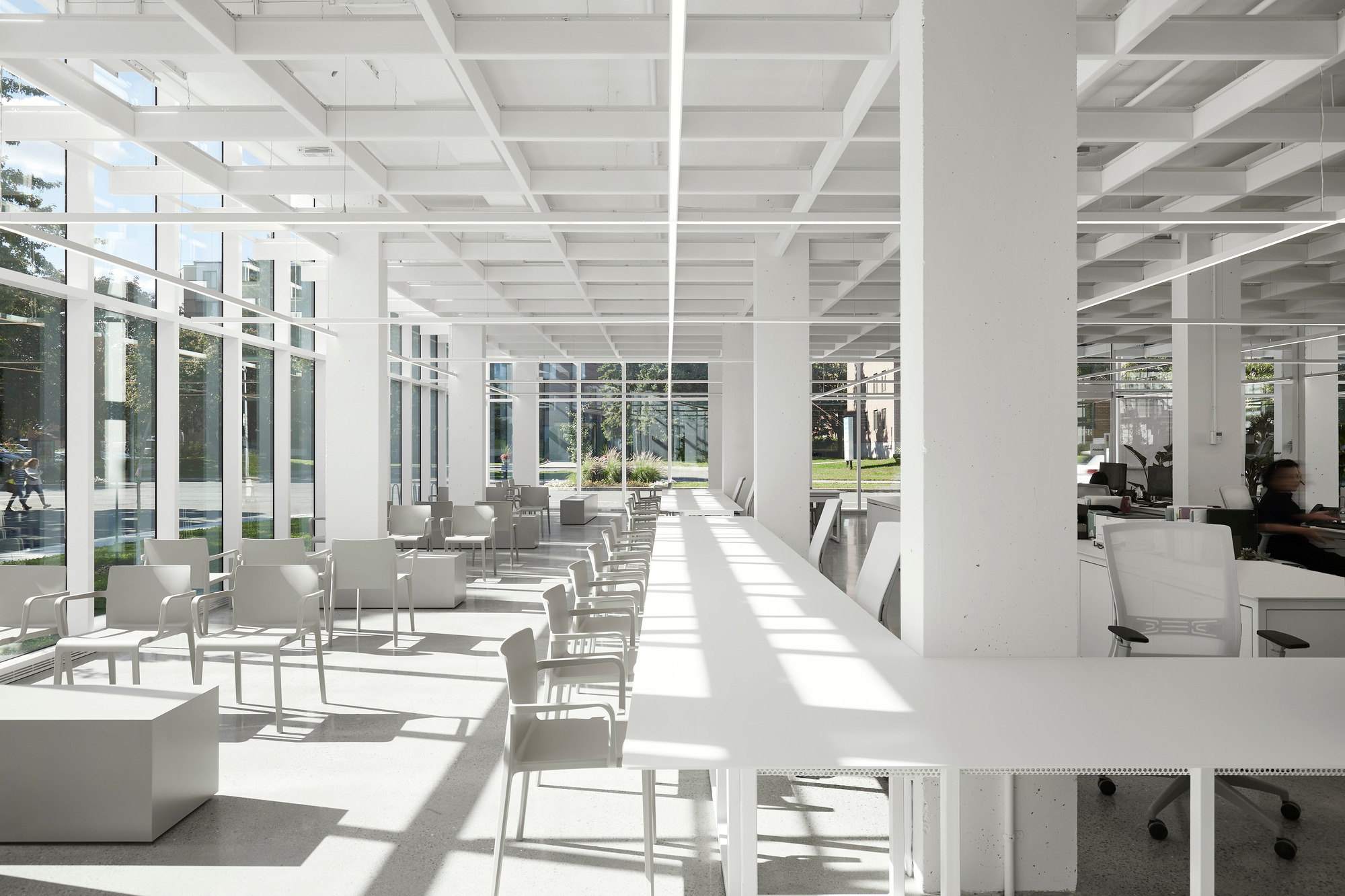 Light-filled interior with waffle slab ceiling and floor-to-ceiling windows casting geometric shadows across white furniture