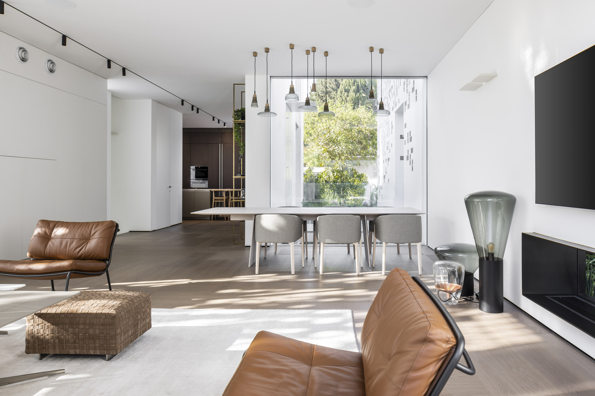 Open living and dining space with leather seating and pendant lights overlooking garden window