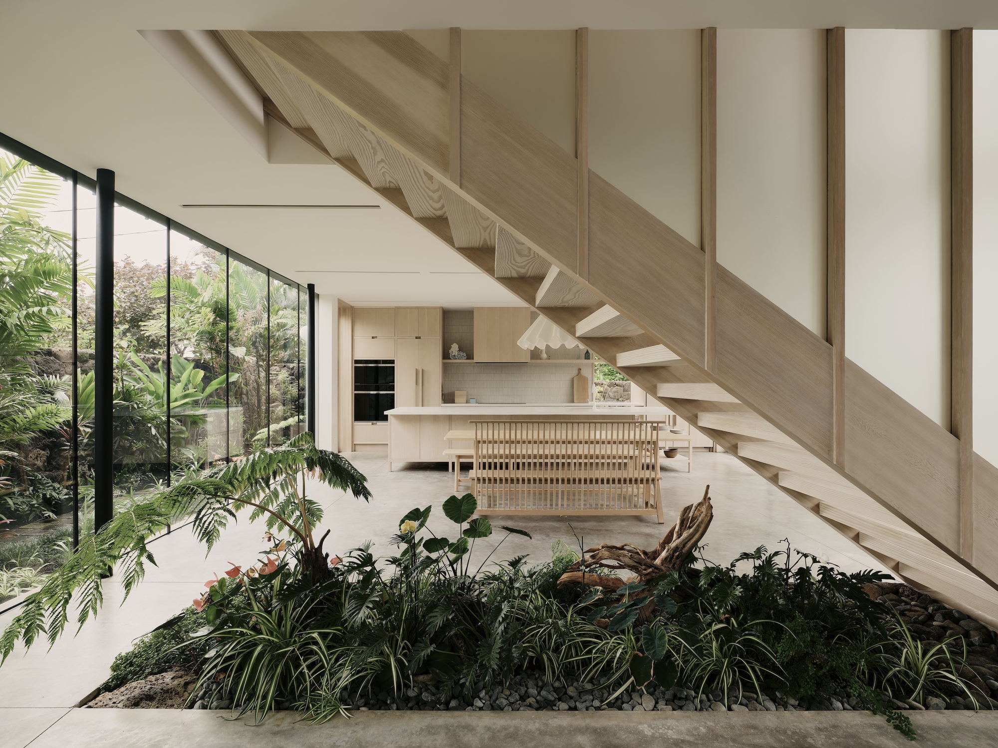 Interior planted bed beneath the timber staircase with kitchen island visible beyond