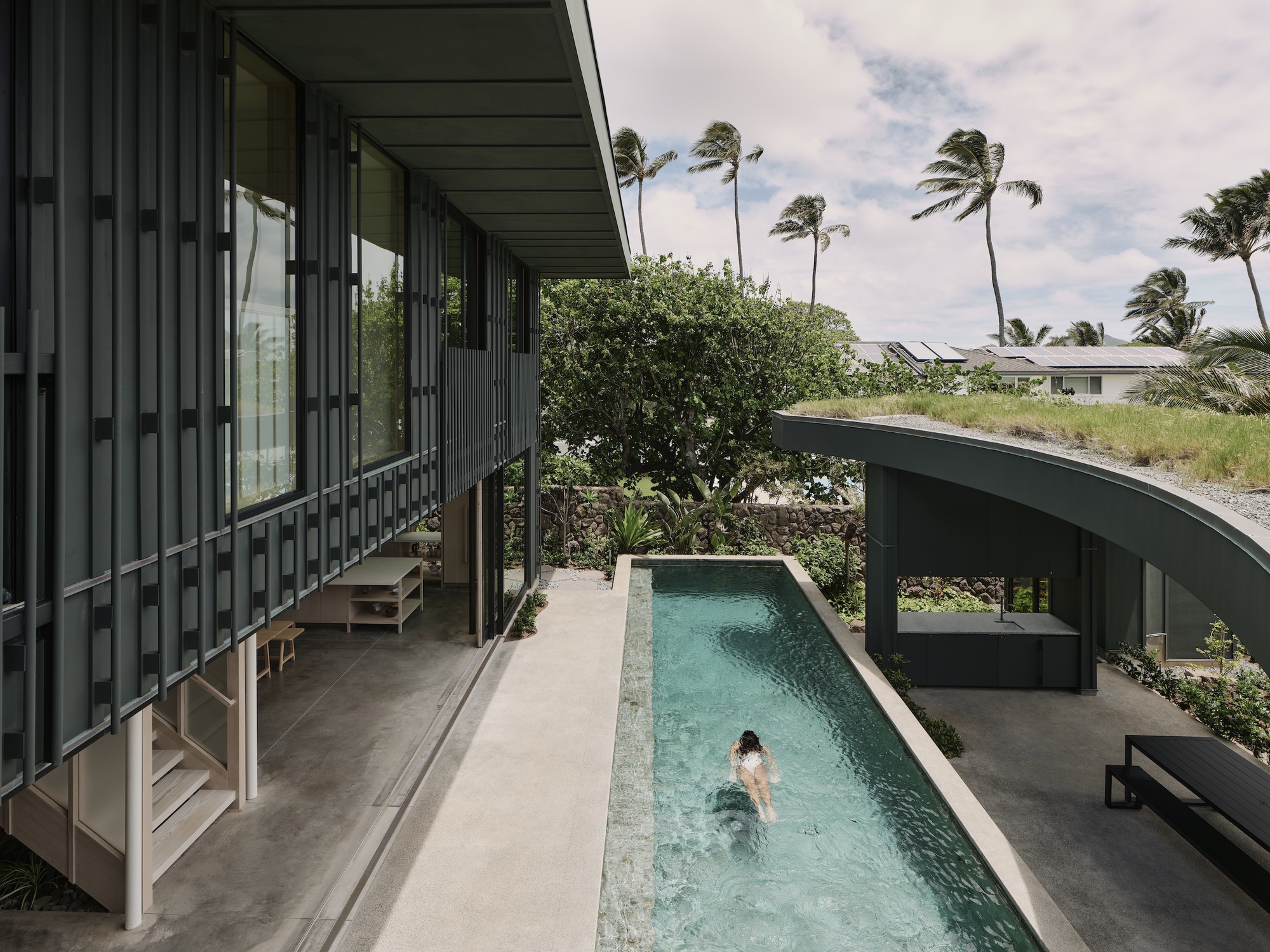 Covered upper terrace overlooking the lap pool where a swimmer glides through the water
