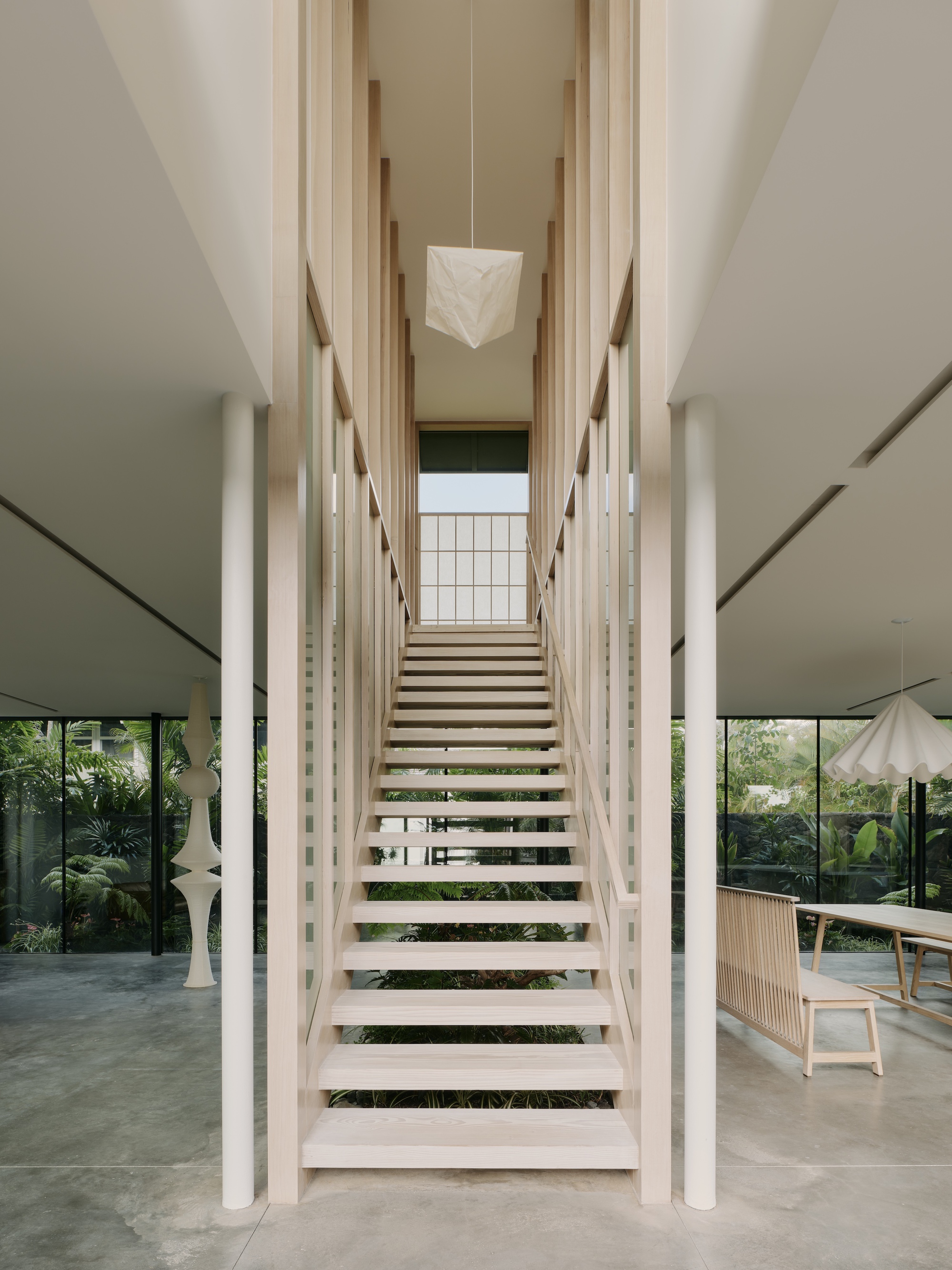 Timber staircase with open treads flanked by white columns and vertical timber slats